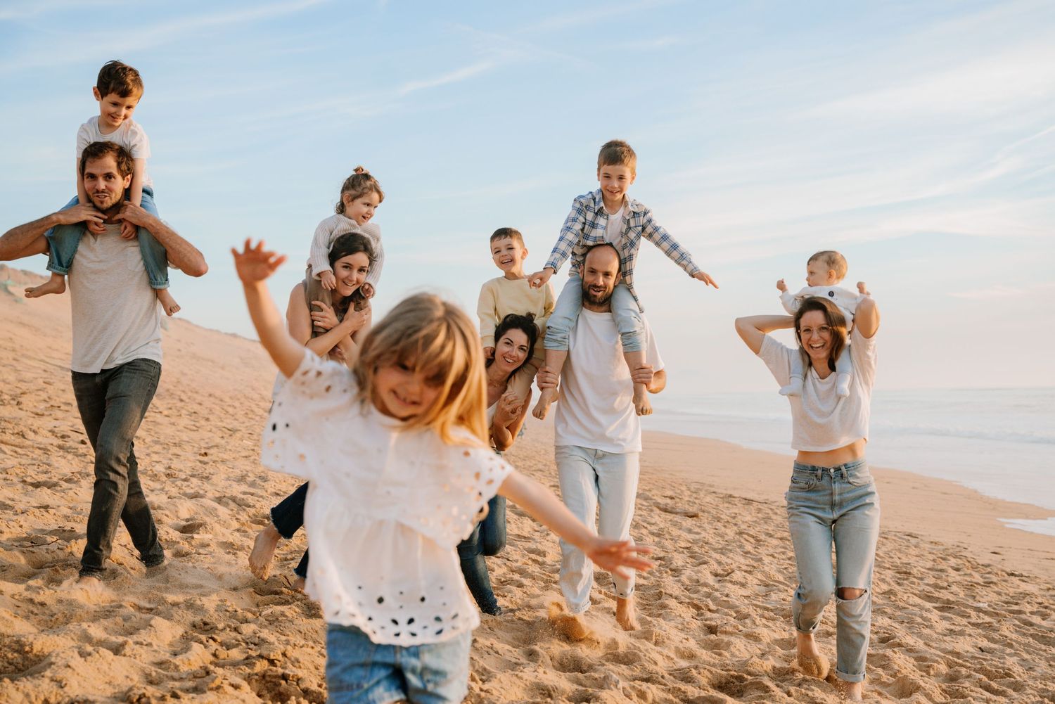 A family plays together and poses joyfully on a sunny beach during golden hour.
