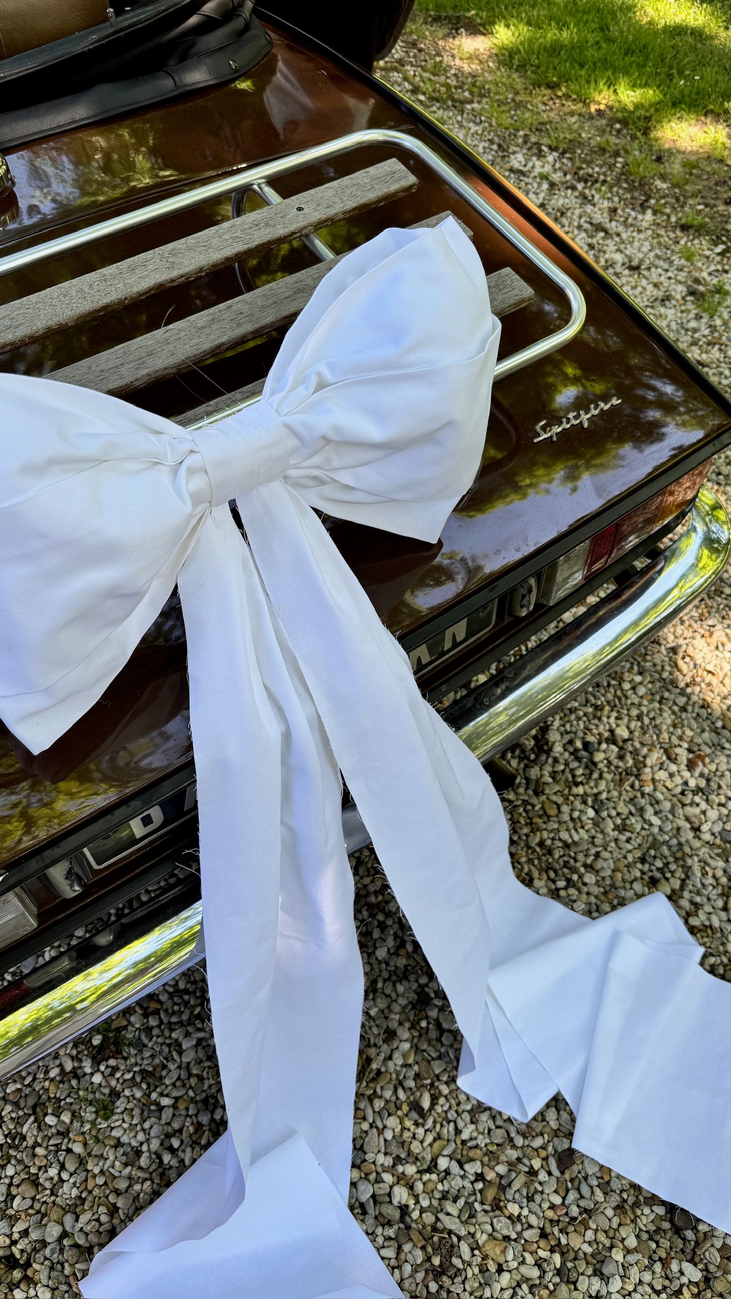 Large white decorative bow displayed on shiny black surface outdoors.