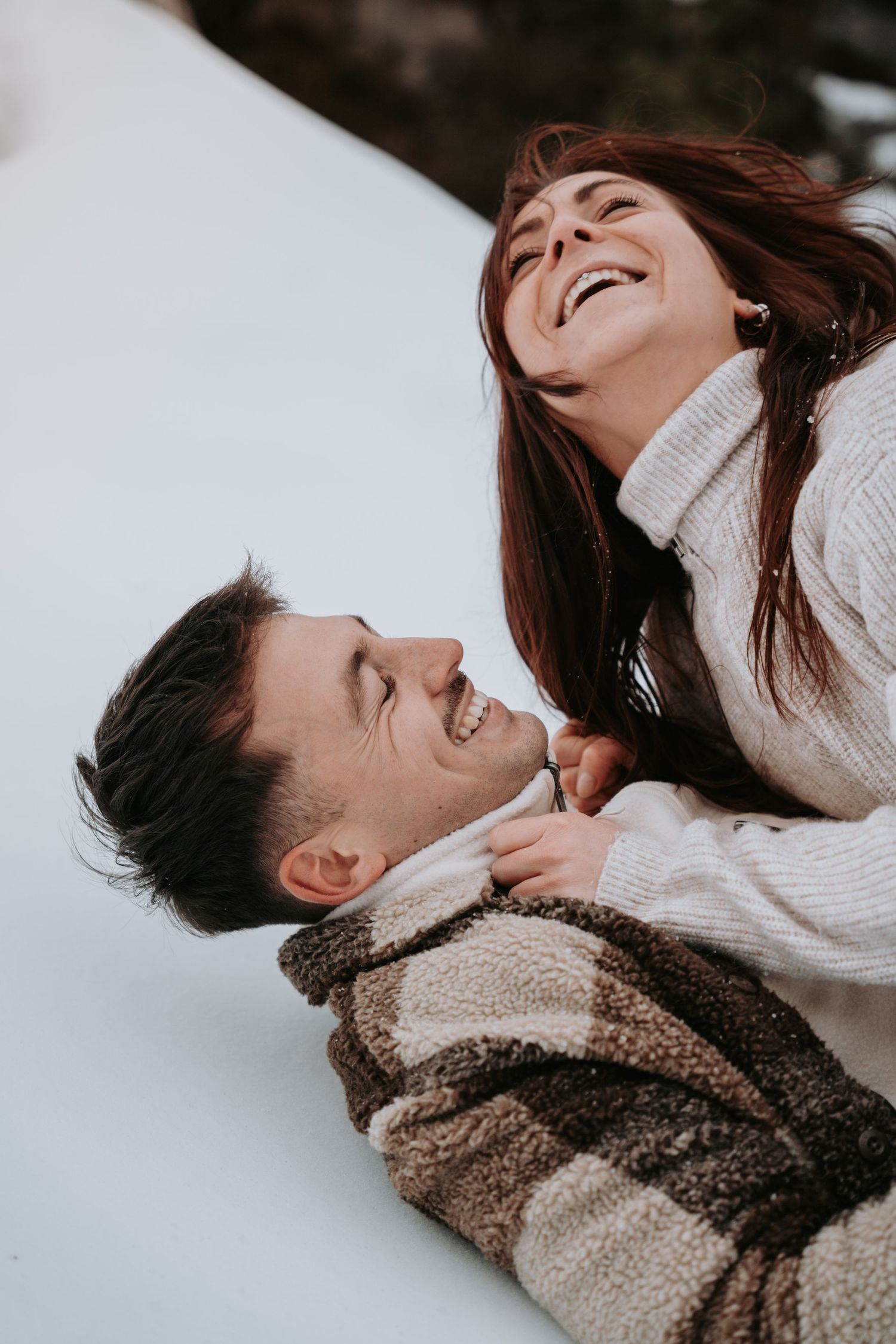 A playful winter couples photoshoot with laughter and intimate moments in the snow.
