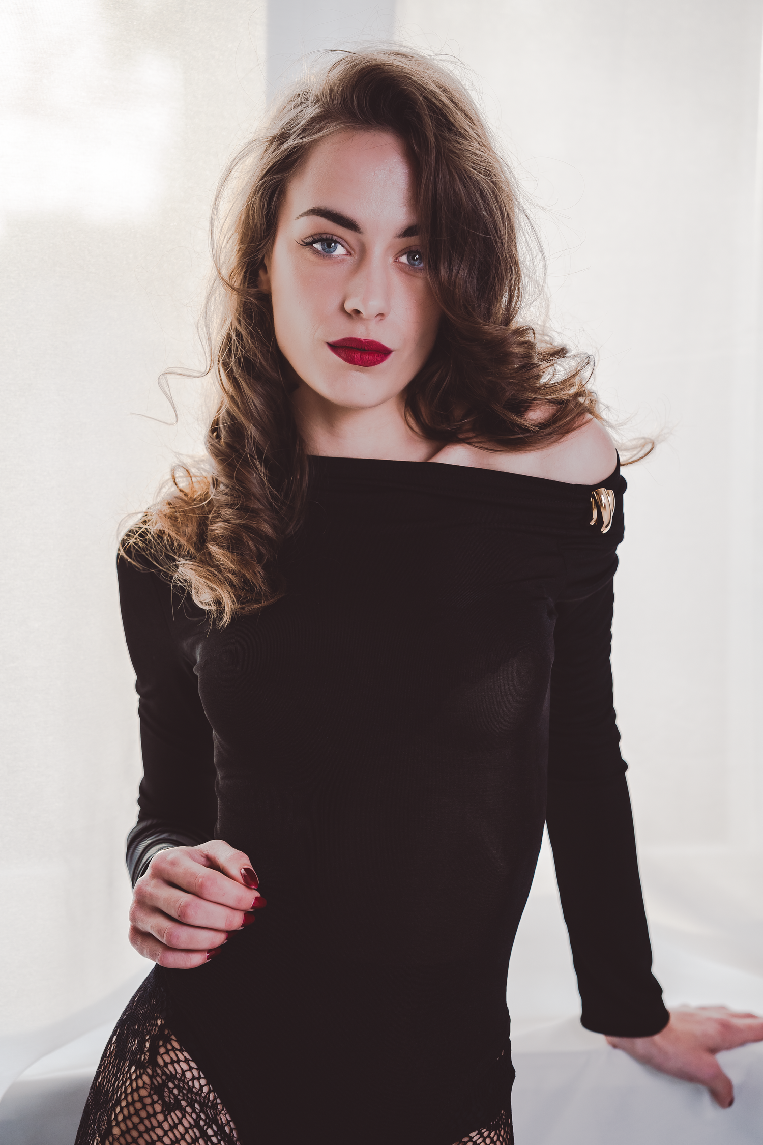 Modeserie med svart off-shoulder-topp, dramatisk makeup och stylade lockar.