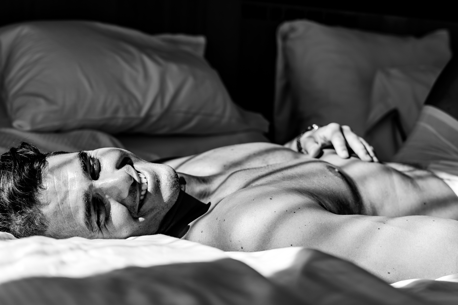 Svartvit fotoserie med person liggande i säng med dramatisk ljussättning och skuggor.
