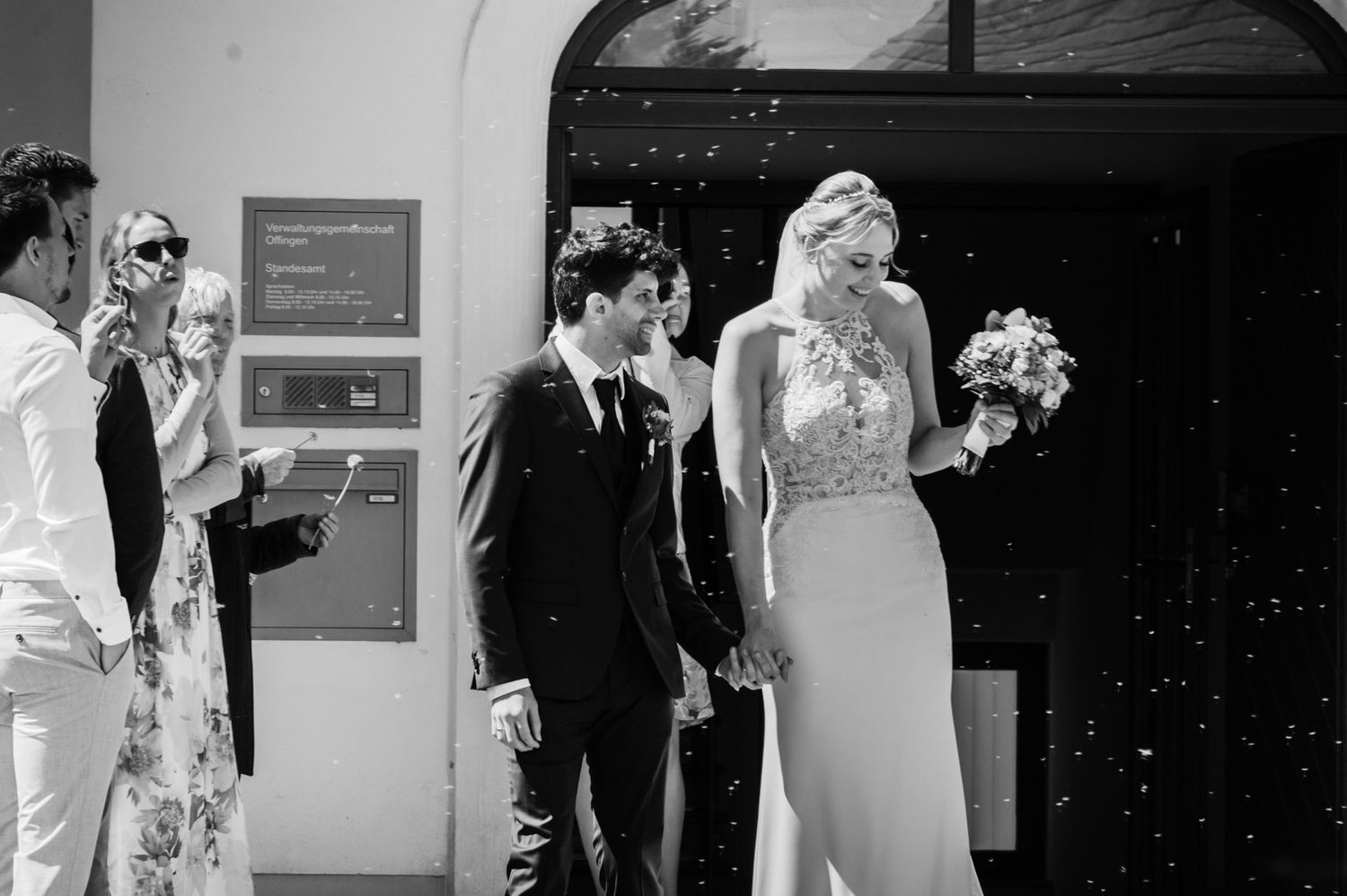 Black and white photo of a bride and groom exiting a building with confetti falling around them.
Carmela Kolb, Photographer