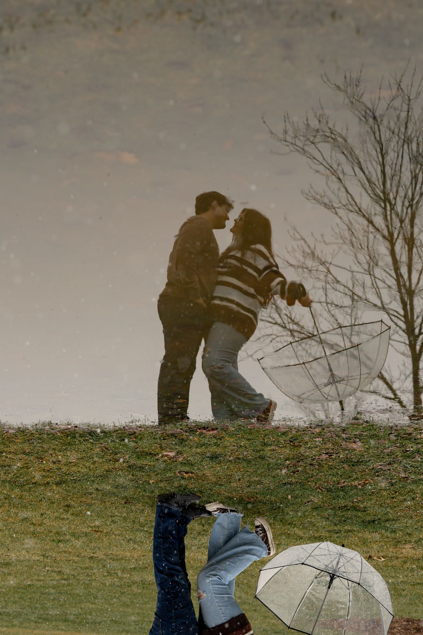 Silhouettes of a couple reflected in water during a snowy day.