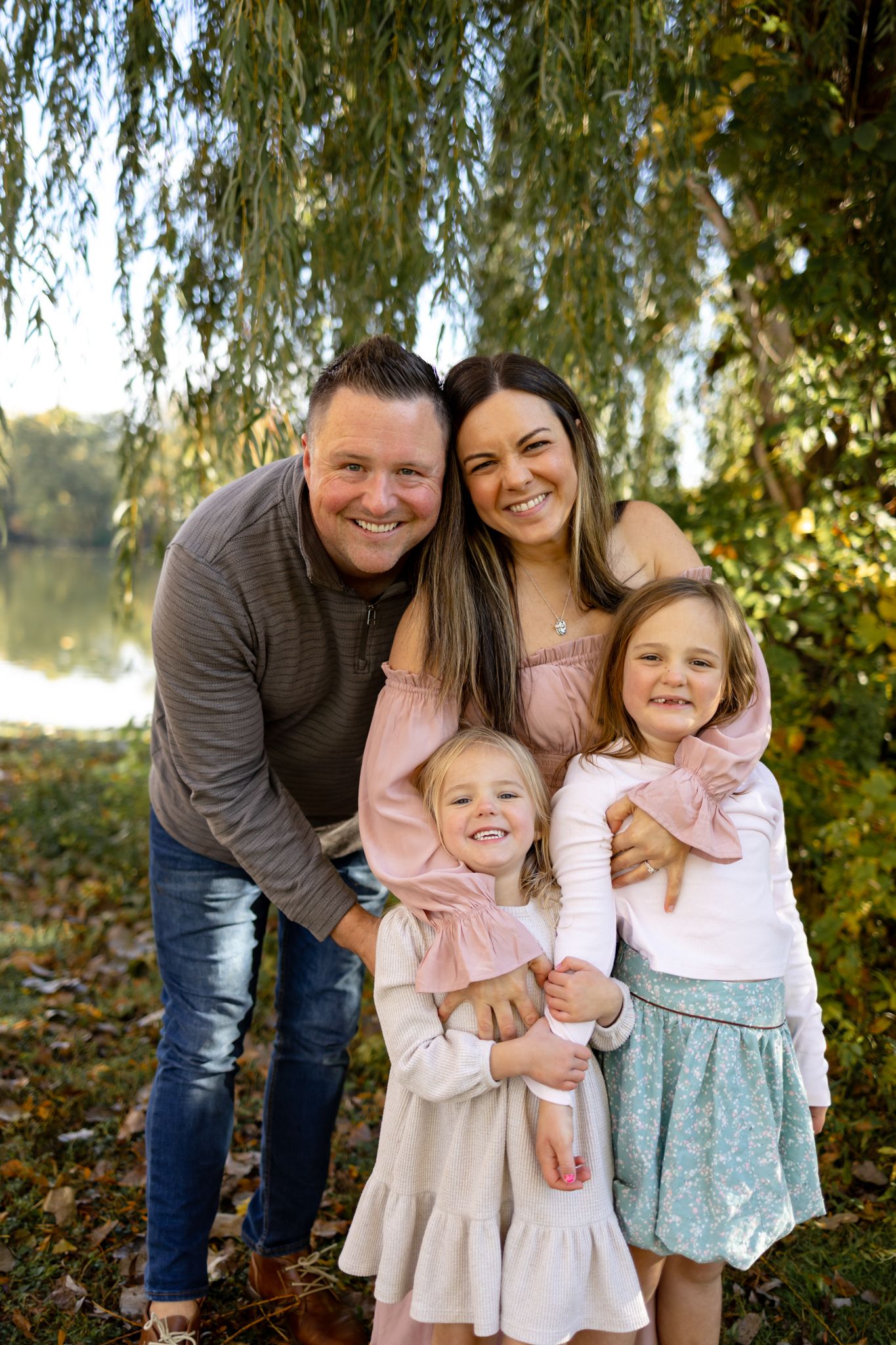 Happy family group hugging and smiling together under fall foliage.