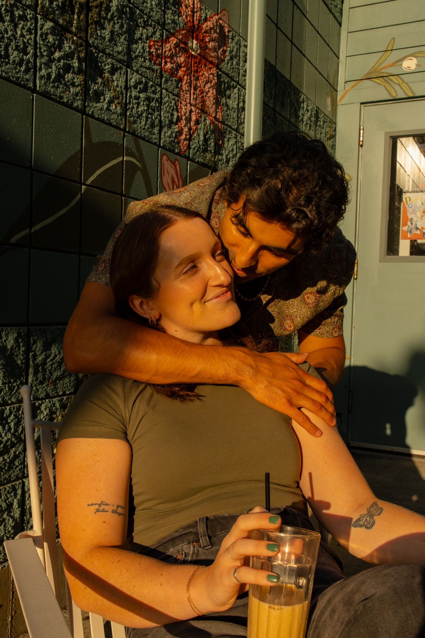 Couple embraces on outdoor patio chair during golden hour sunlight.