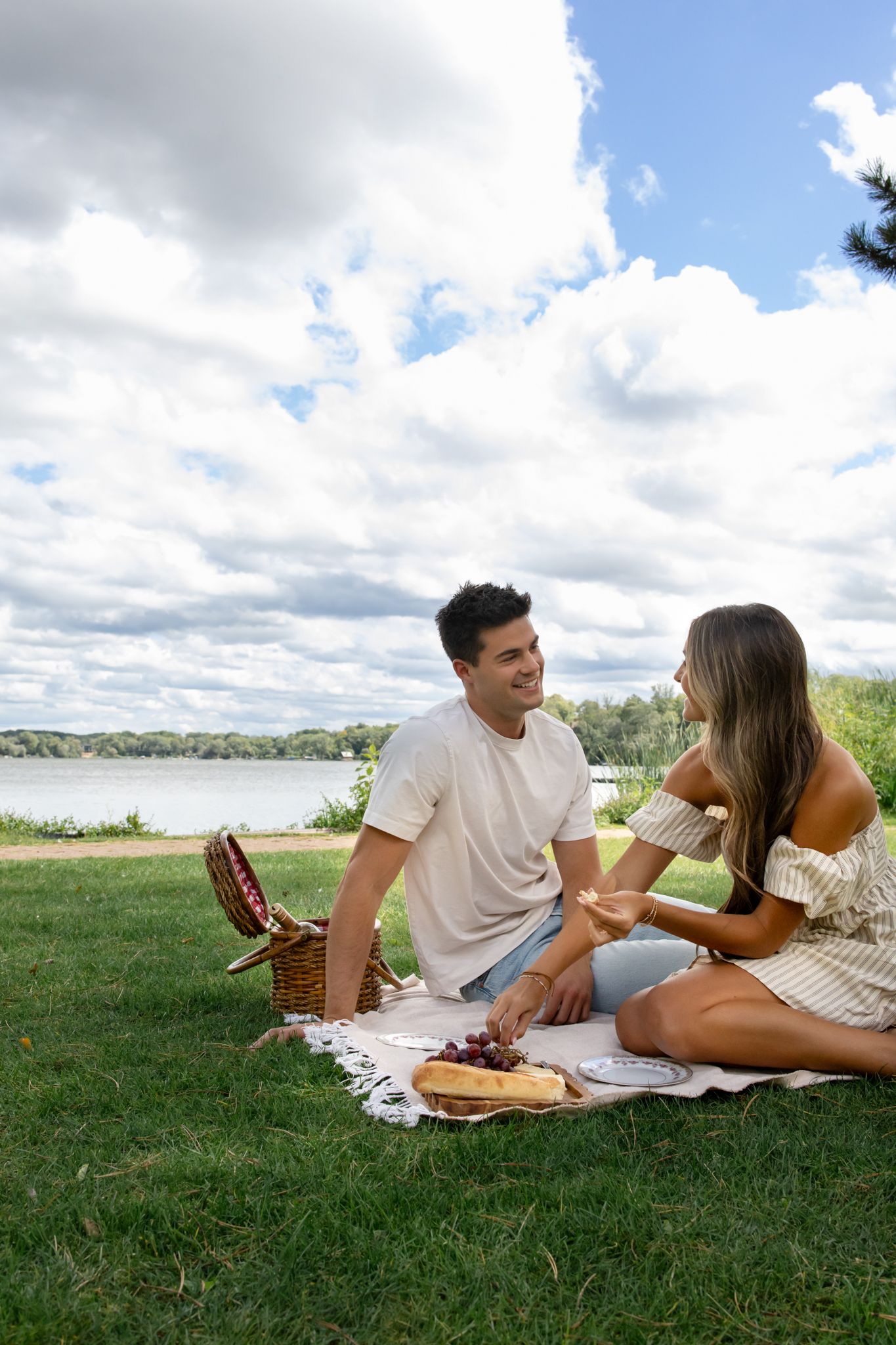 A couple enjoying a romantic picnic by the lake on a sunny summer day.