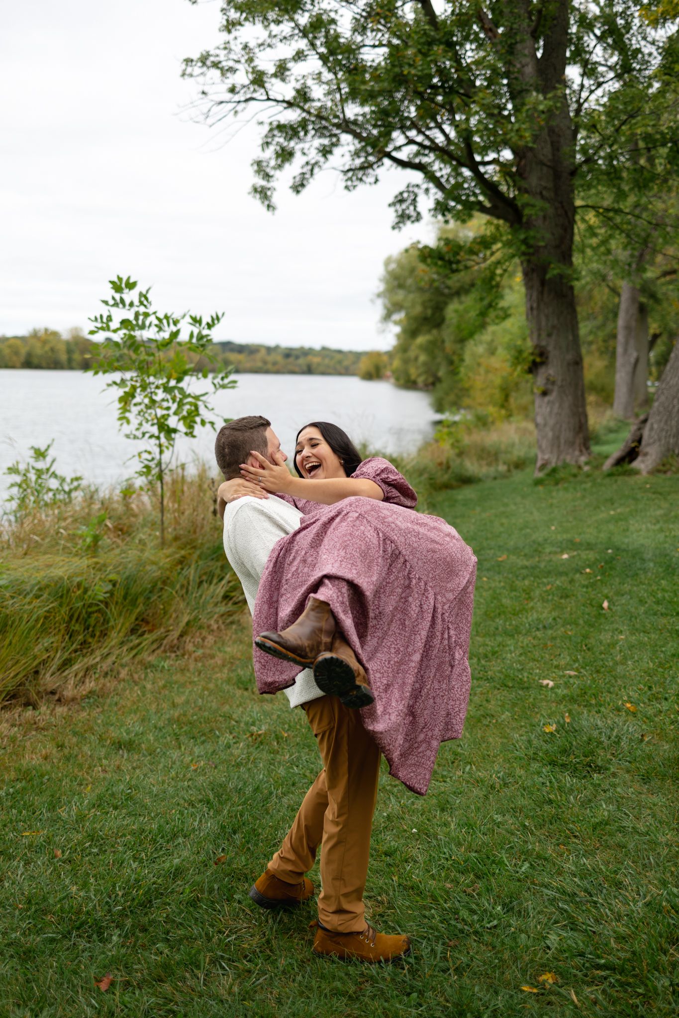 A romantic dance scene unfolds on grassy lakeside with flowing mauve dress and autumn trees.