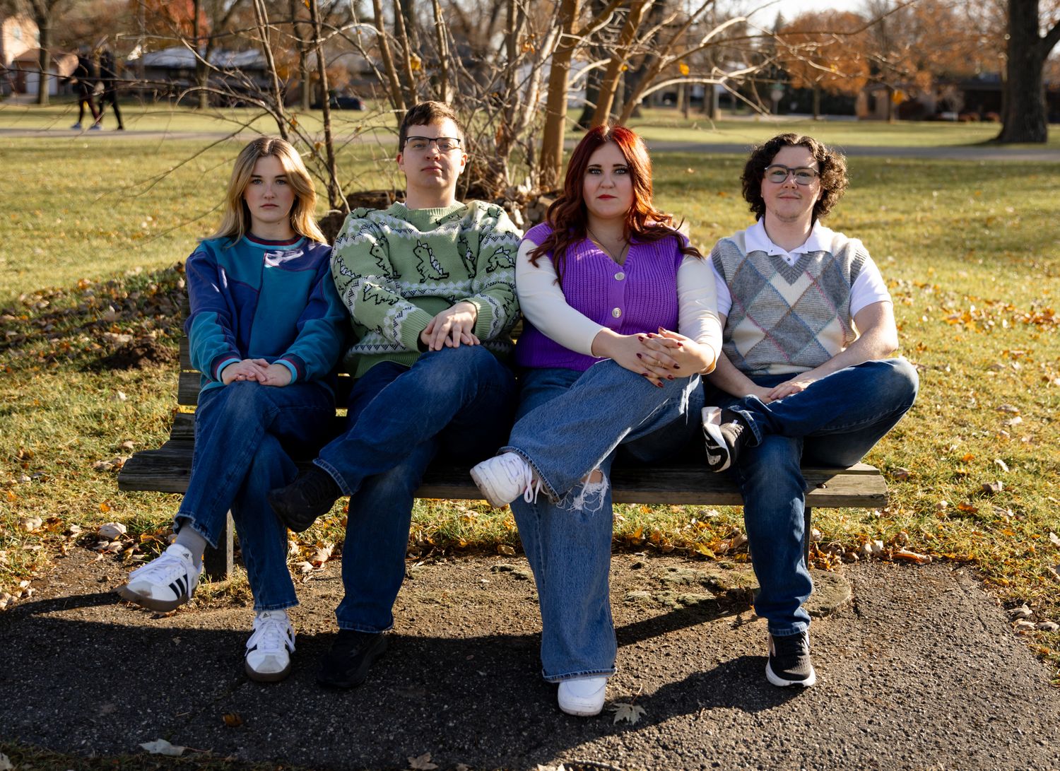 People relaxing on a park bench surrounded by autumn foliage.
