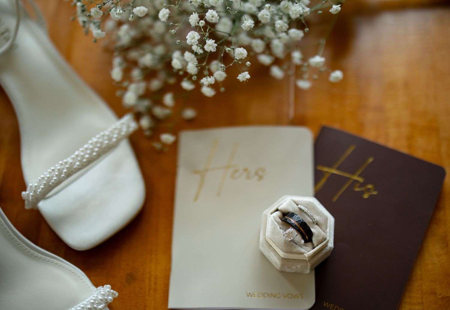 Wedding rings and delicate baby's breath flowers arranged on wooden surface.