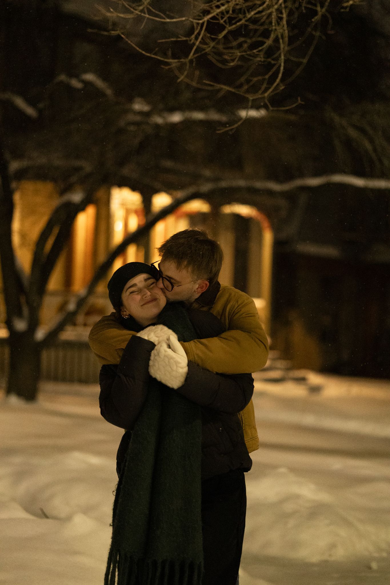 A romantic winter embrace between two people in the snowy evening.