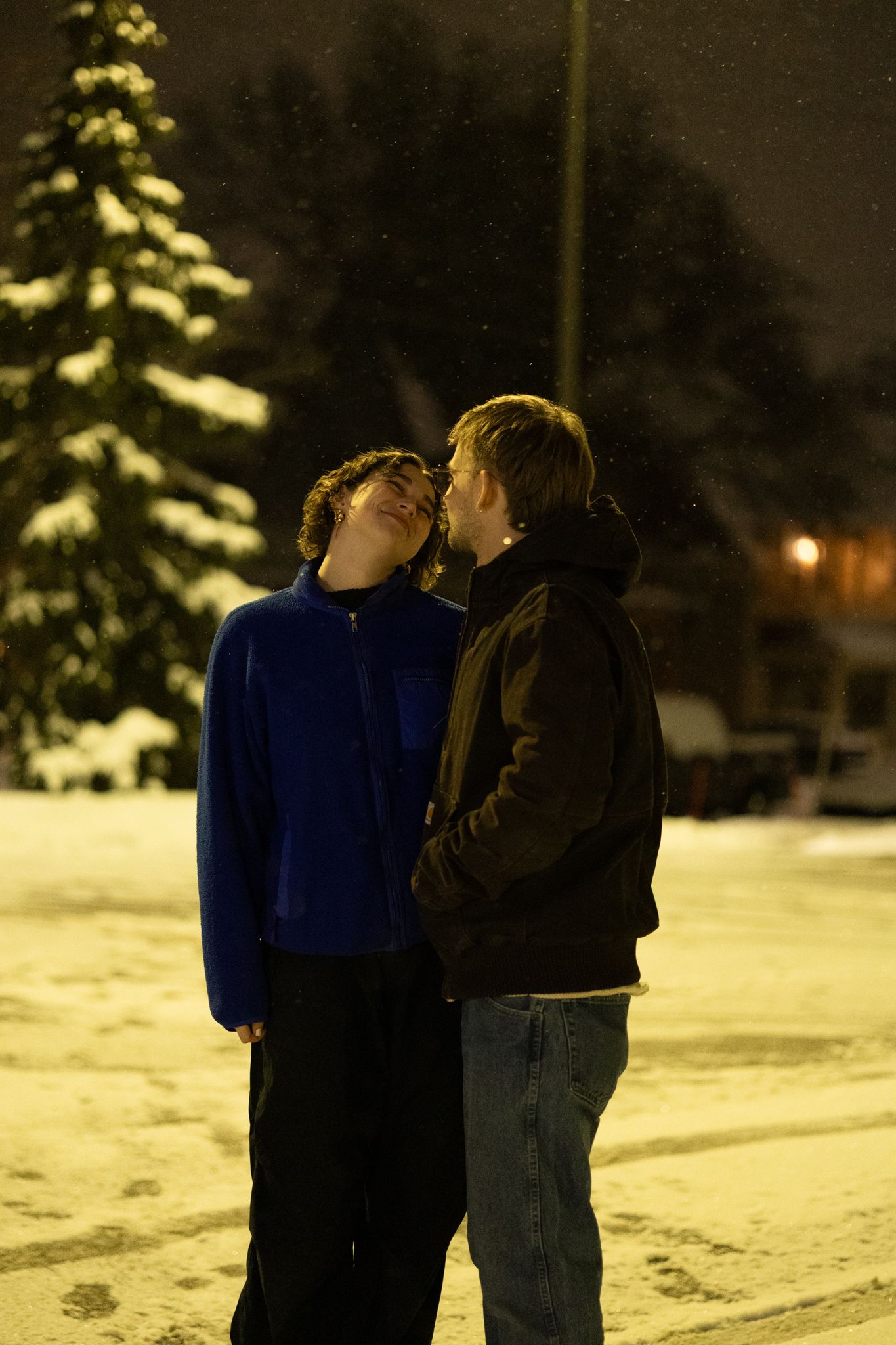 Two figures standing close together in a snowy landscape at night.
