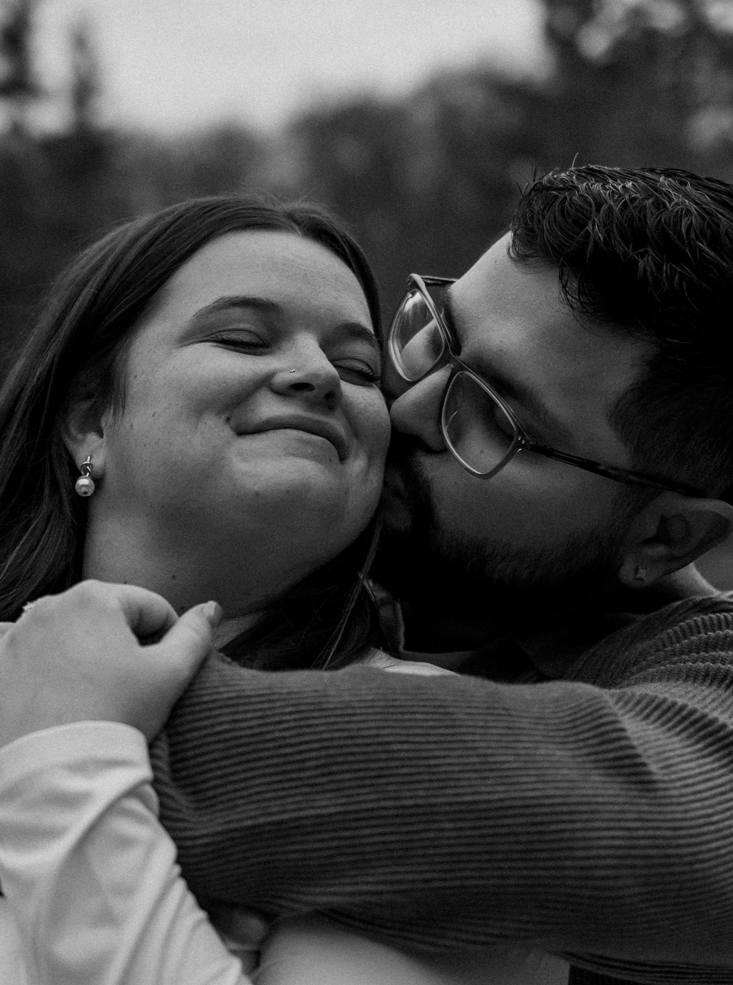 Close-up black and white photo of couple sharing an intimate embrace outdoors.