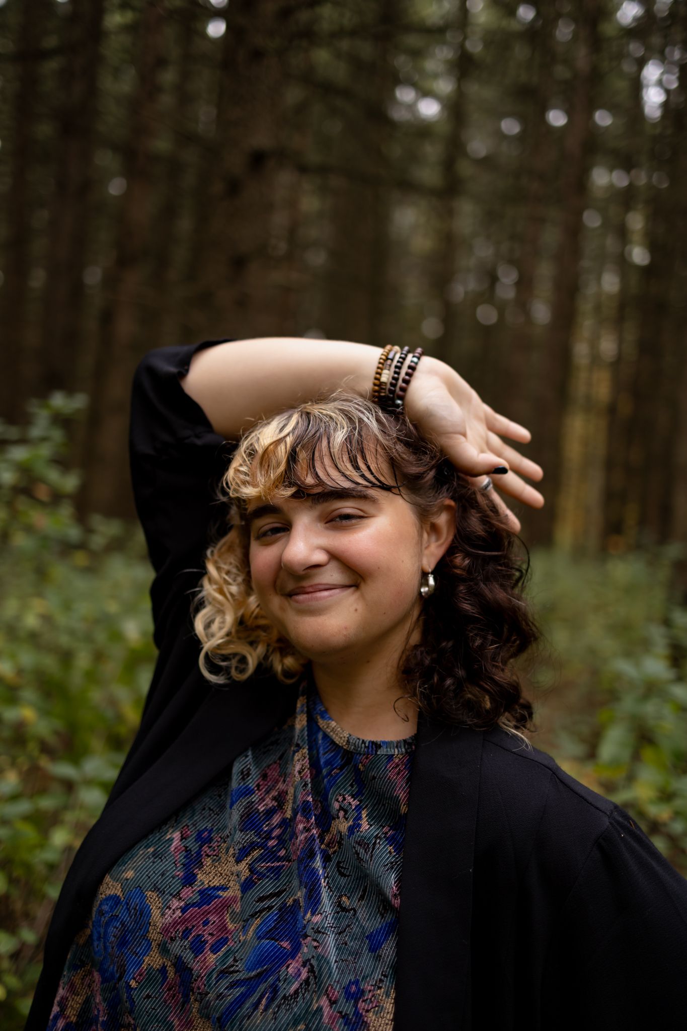 Candid moment captured in forest with person in patterned top and black jacket.