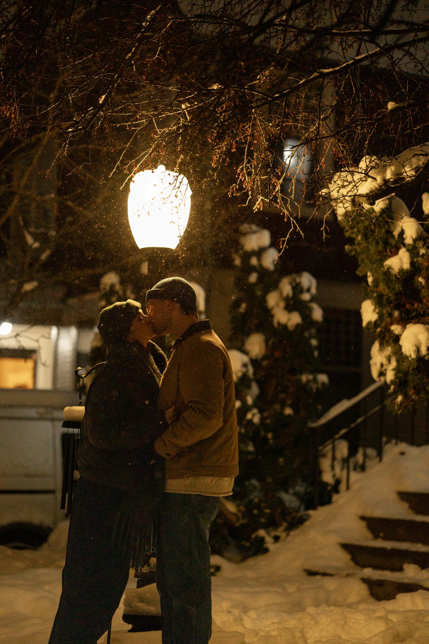 Two people share a romantic moment under glowing lanterns in the snow.