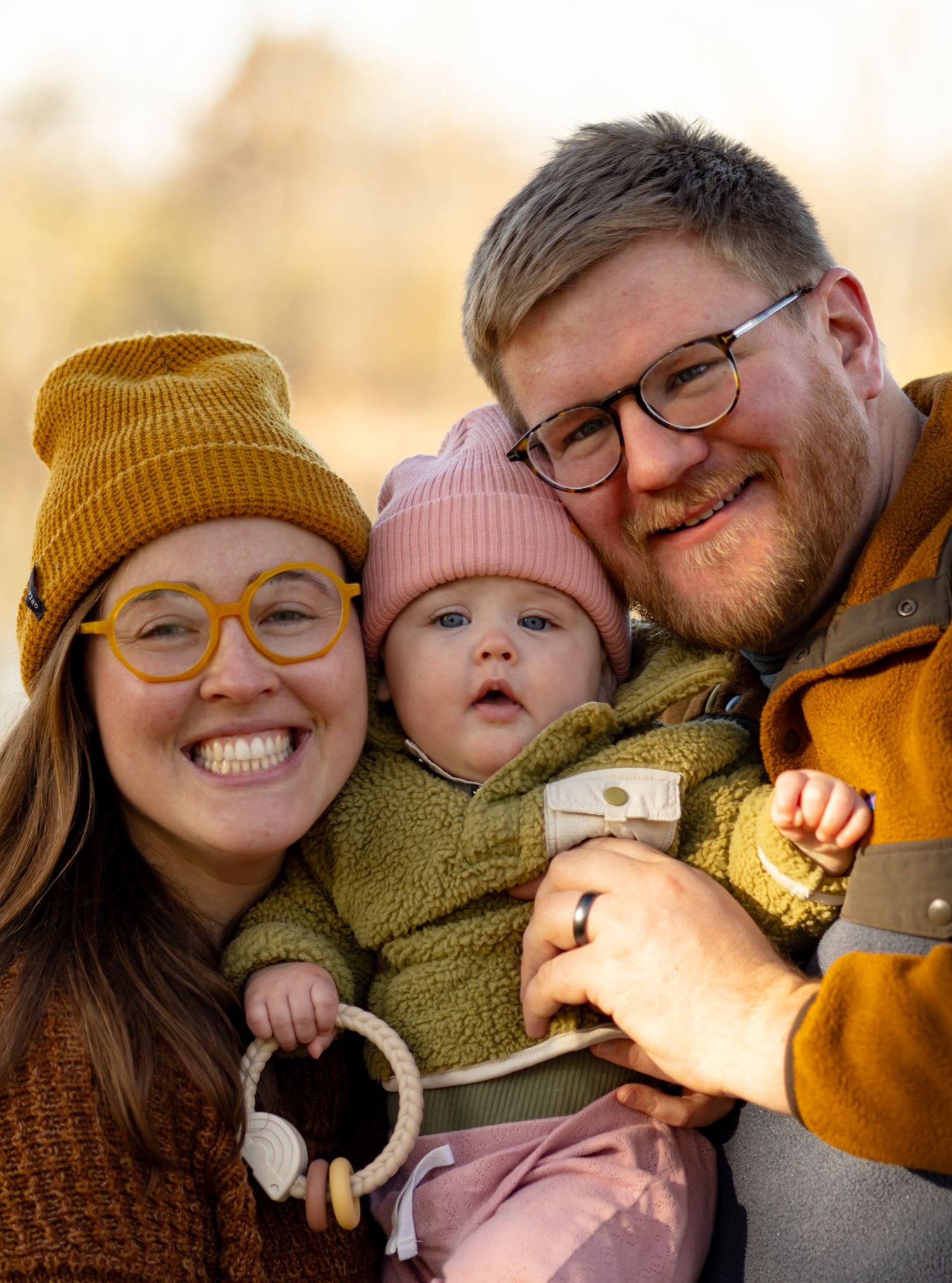 A close-up portrait of a family sharing laughter and cuddles in warm autumn clothing.