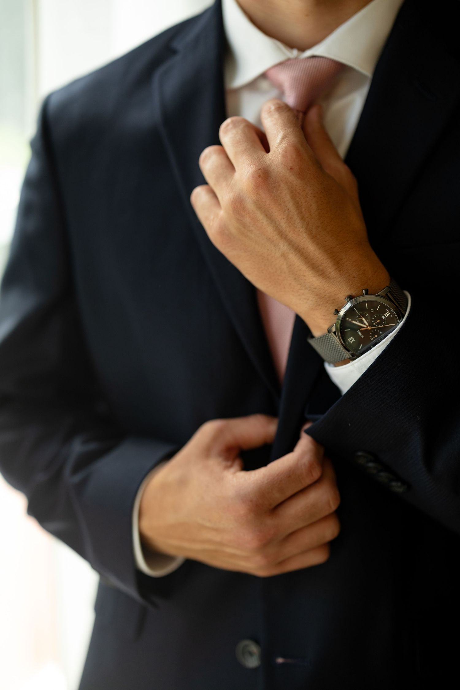 Professional photo series of someone adjusting their suit and watch.