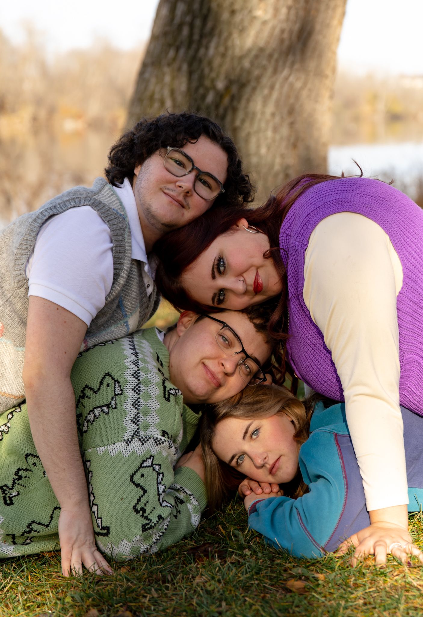 People lounging together on grass wearing colorful sweaters in warm autumn light.
