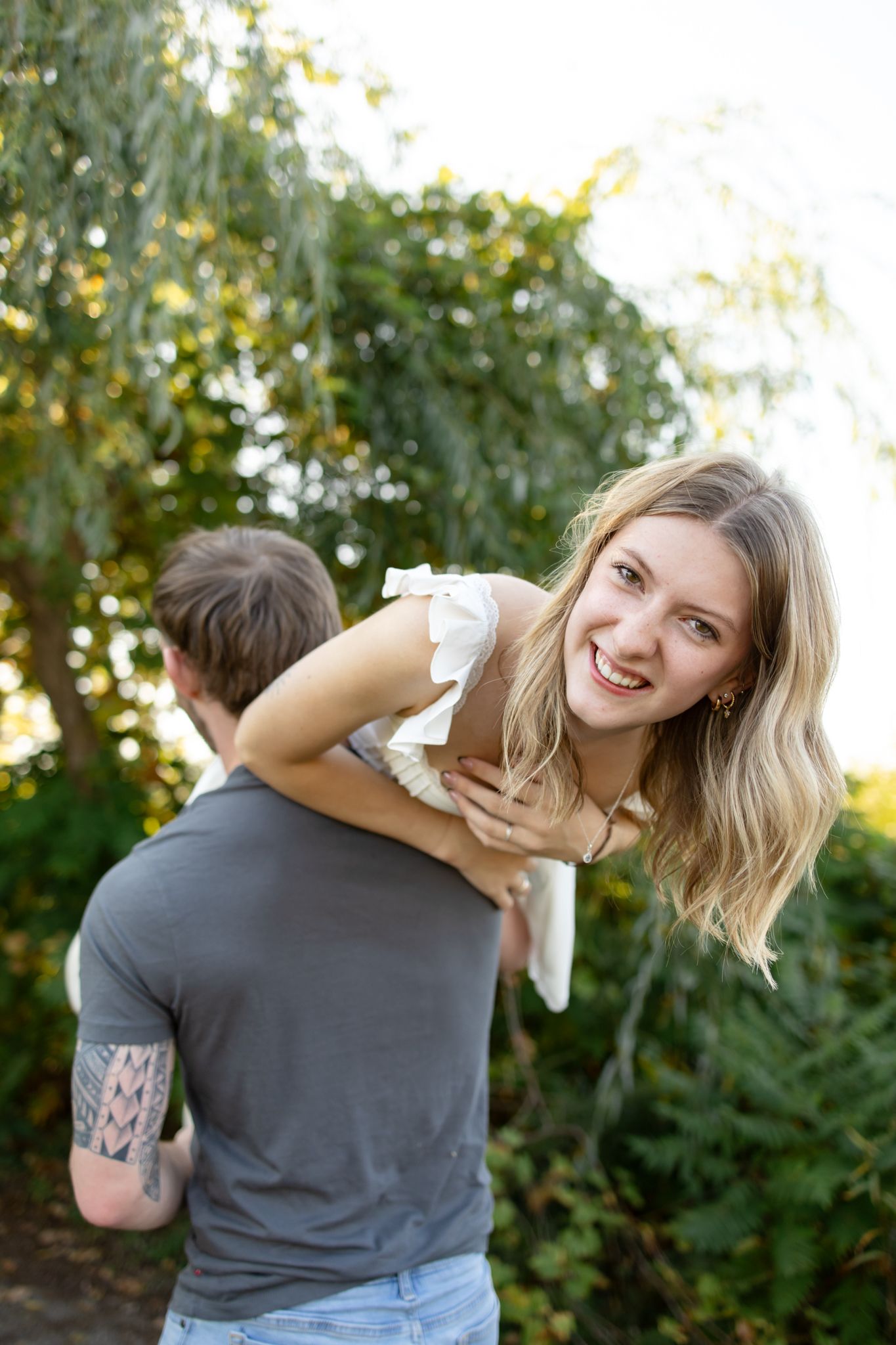 Playful couple sharing joyful moments outdoors against a natural backdrop.