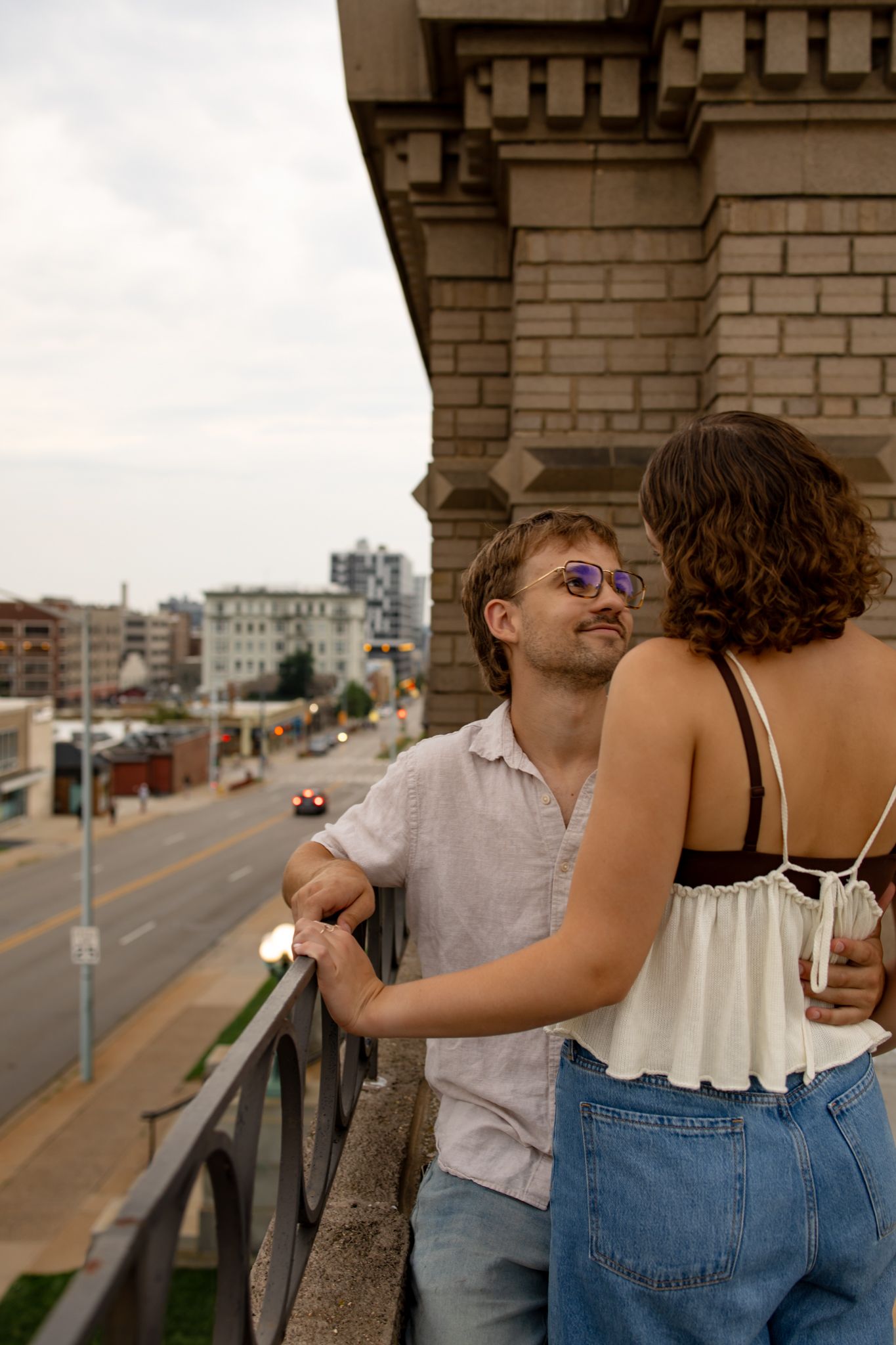 Casual couple enjoying a playful moment on an urban rooftop with city views.