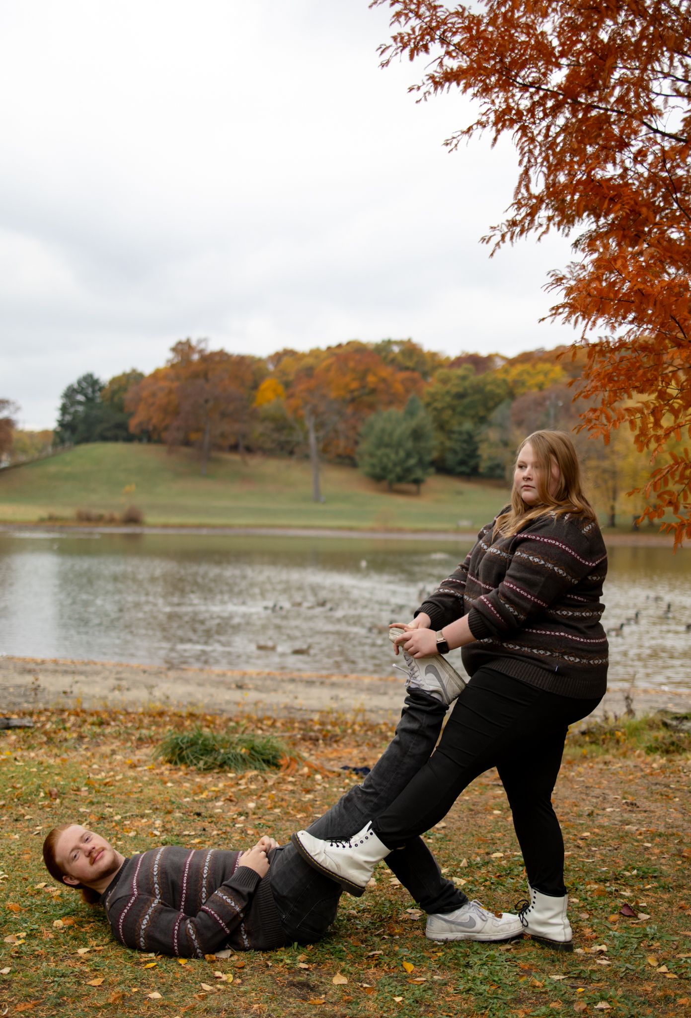 A series of playful autumn photos showing someone rolling on fallen leaves by a lake.