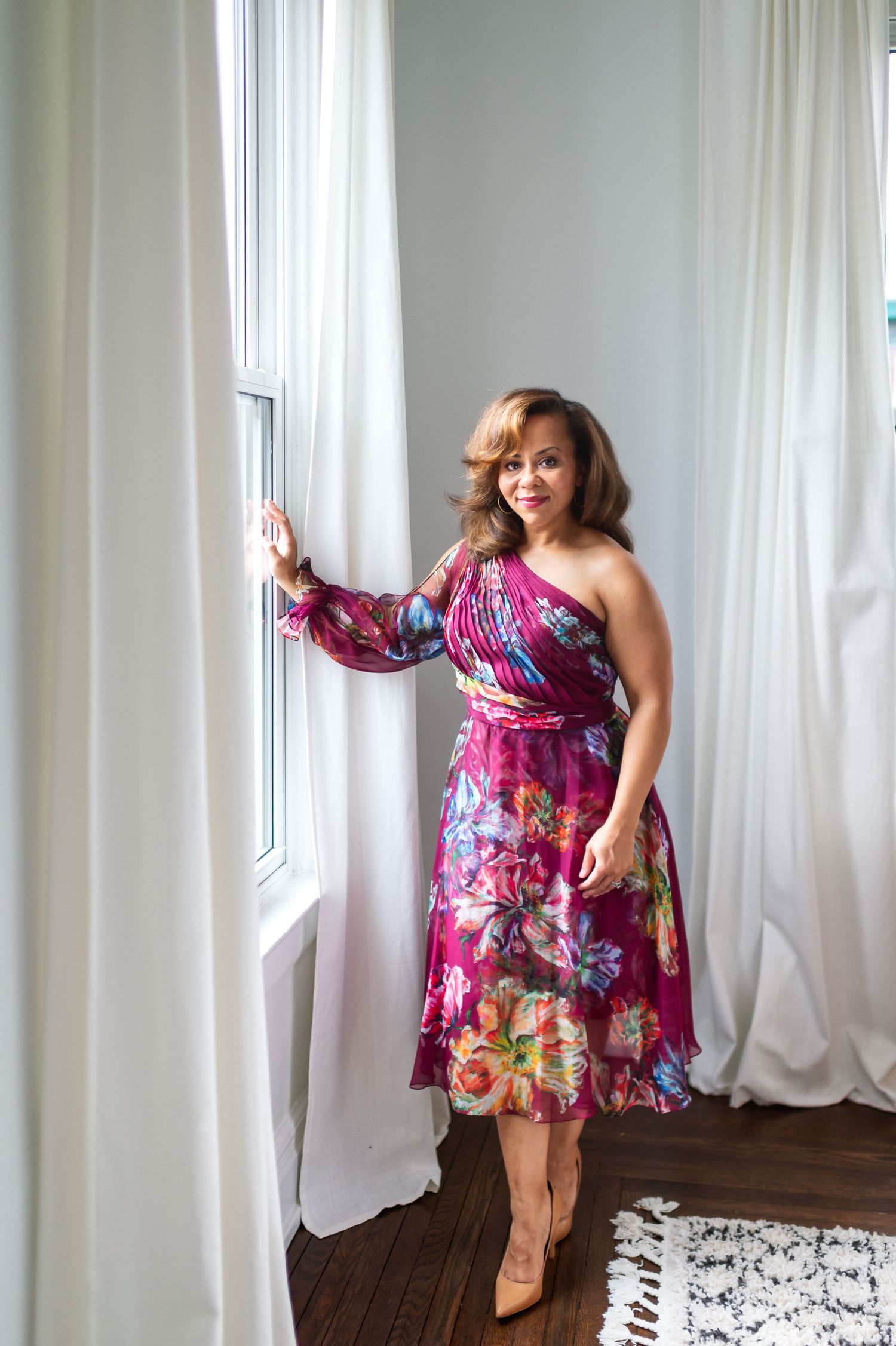 Individual female portrait taken in a living room setting by a window for natural light.