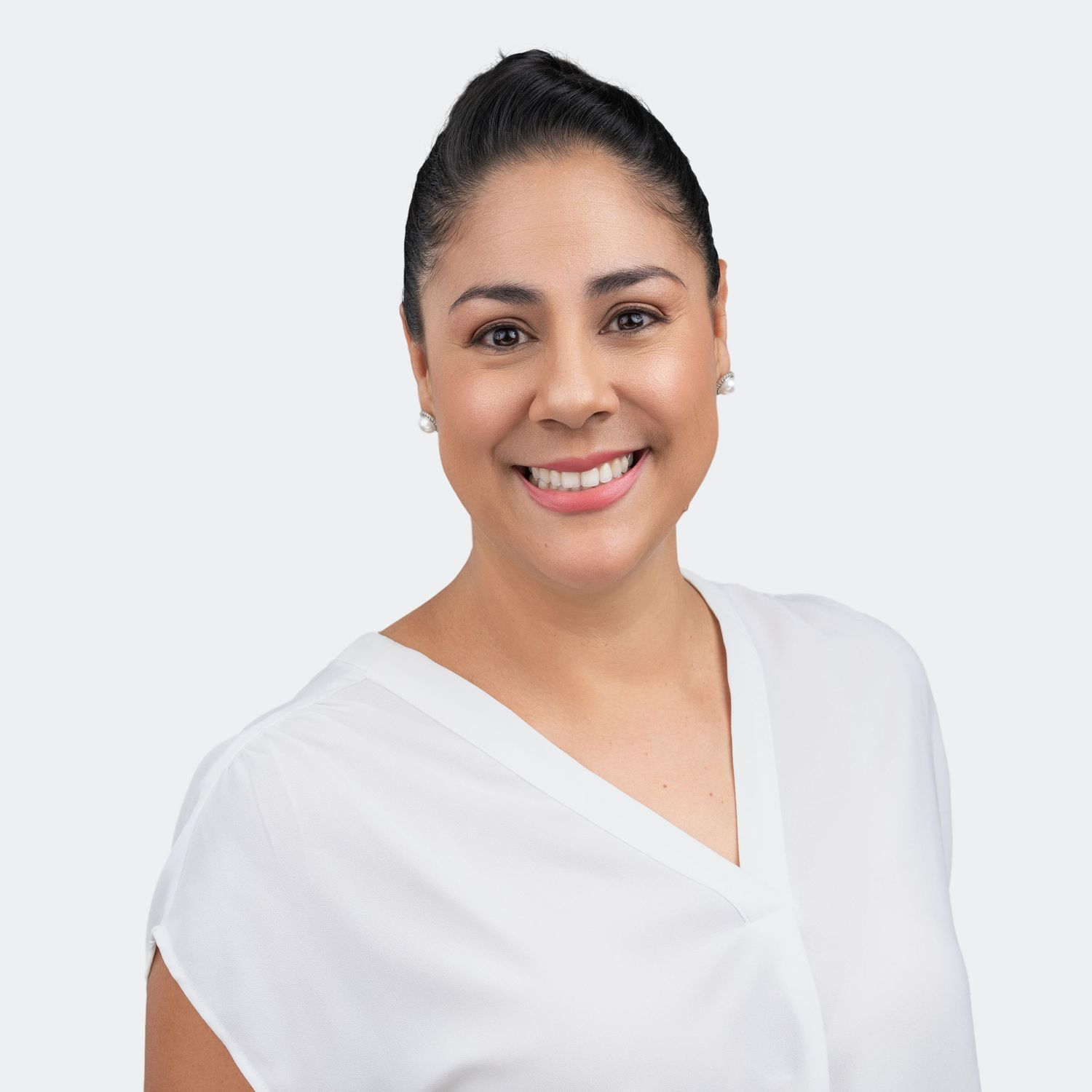 lean, professional headshot of a smiling woman in a white blouse against a neutral studio backdrop.