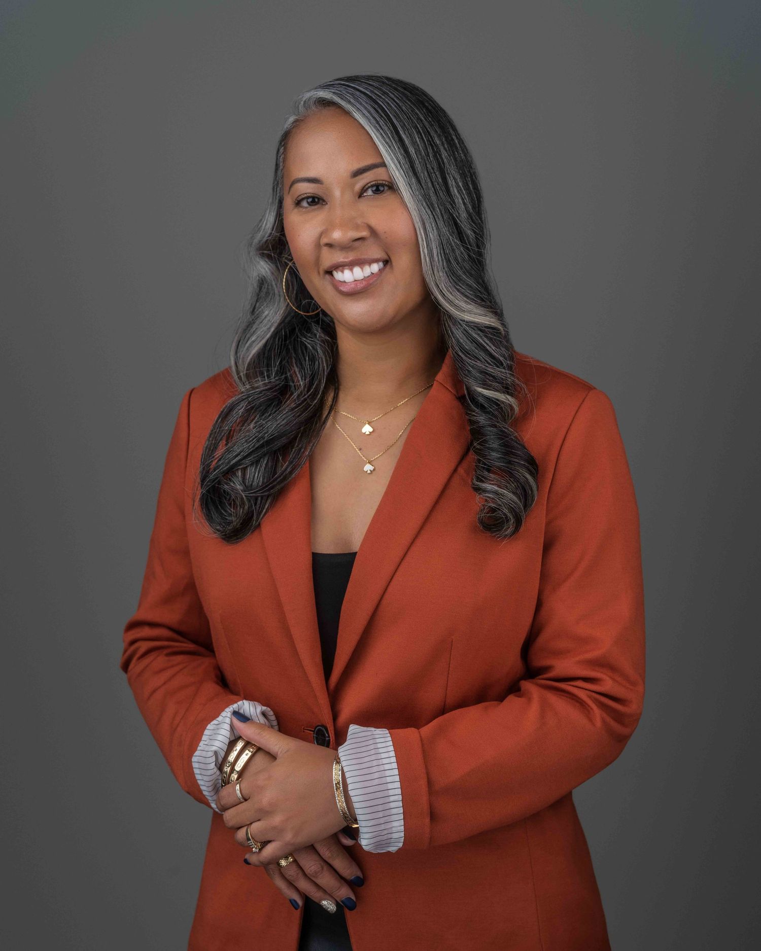 Professional business portrait of an African American woman in a black blazer, smiling against a neutral background.