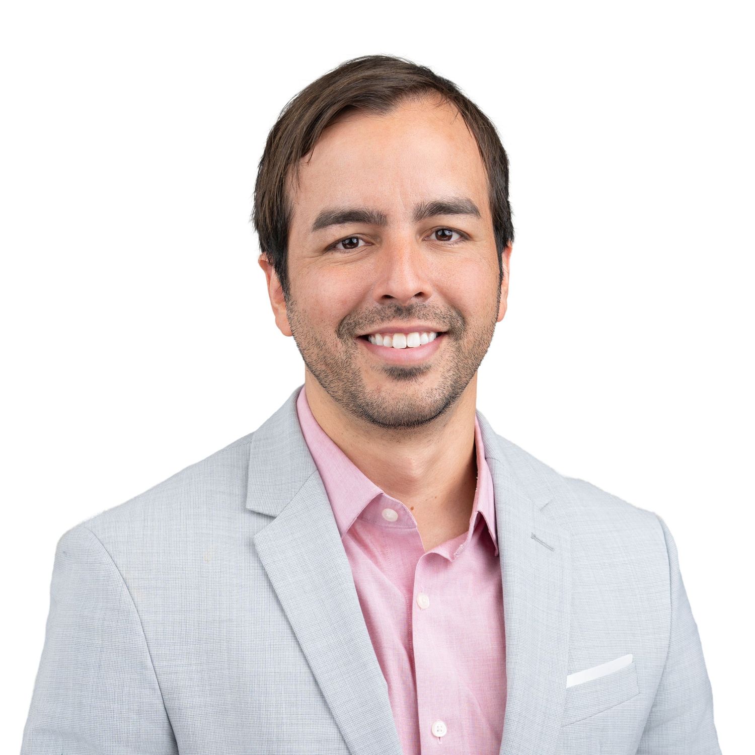 Professional studio headshot of a man in a light pink blazer and white button-down shirt.