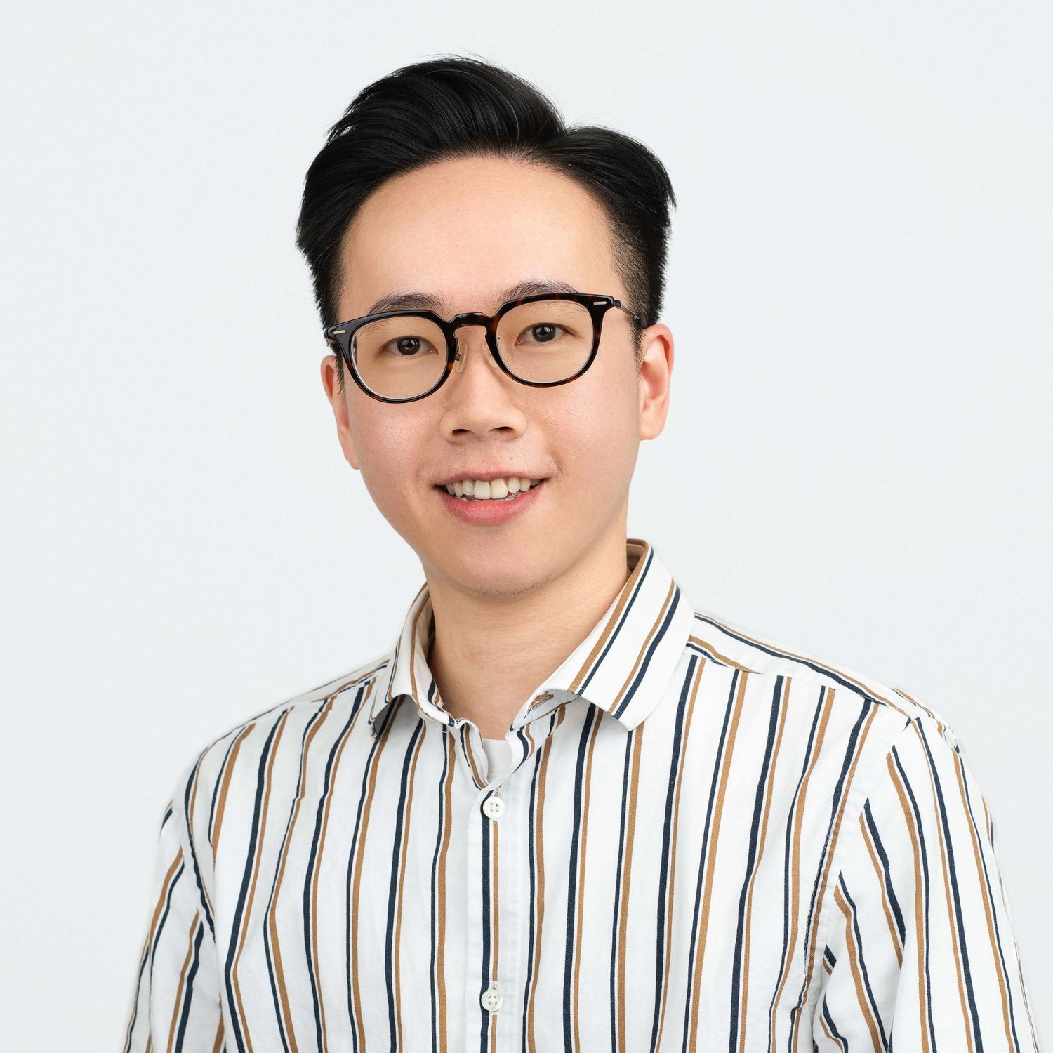 Clean studio headshot of a man with glasses, wearing a black and white striped button-down shirt.
