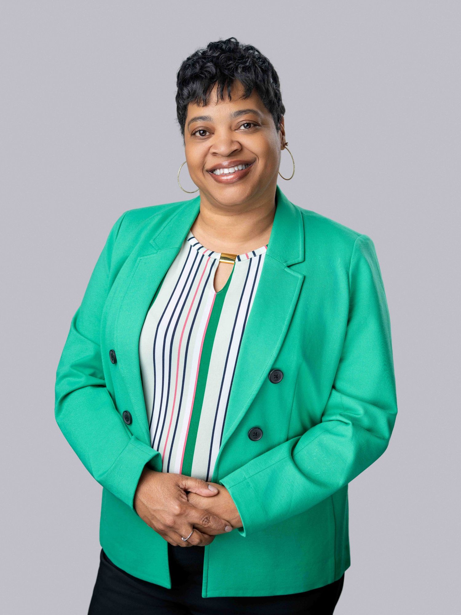 Studio headshot of a woman wearing a green and white striped blouse under a green blazer.