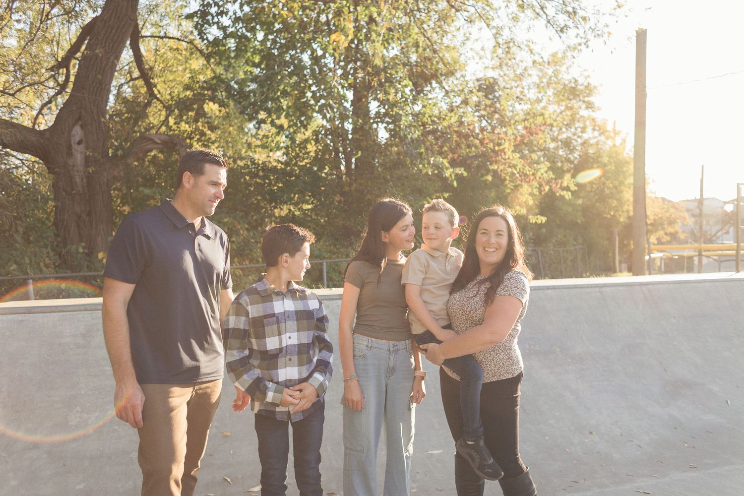 Une famille debout, tous ensemble, éclairés par la lumière du coucher du soleil près d'une rampe de béton.