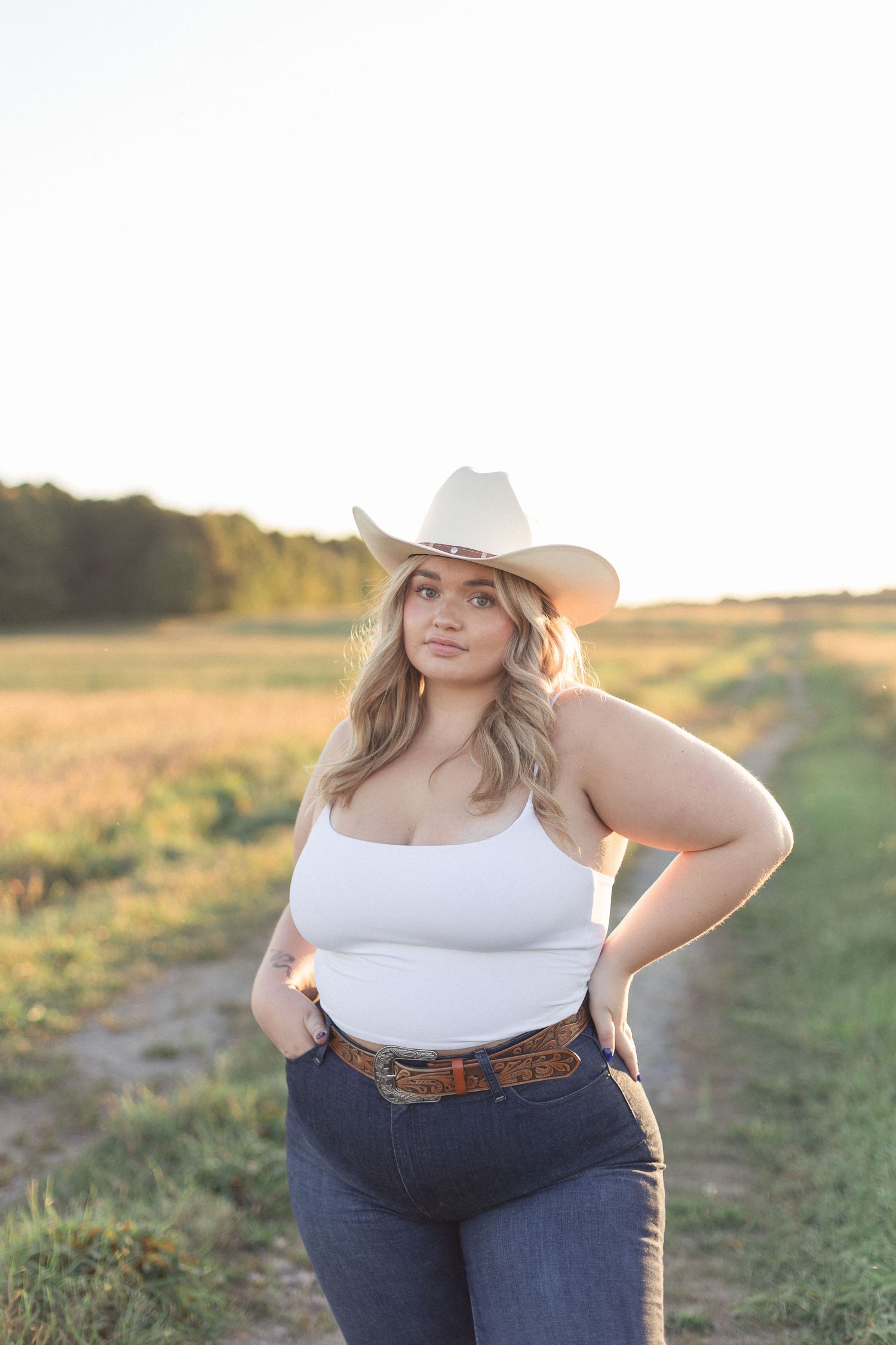 Portrait d'une femme portant un chapeau de cowboy, photographiée en lumière naturelle à l'extérieur.