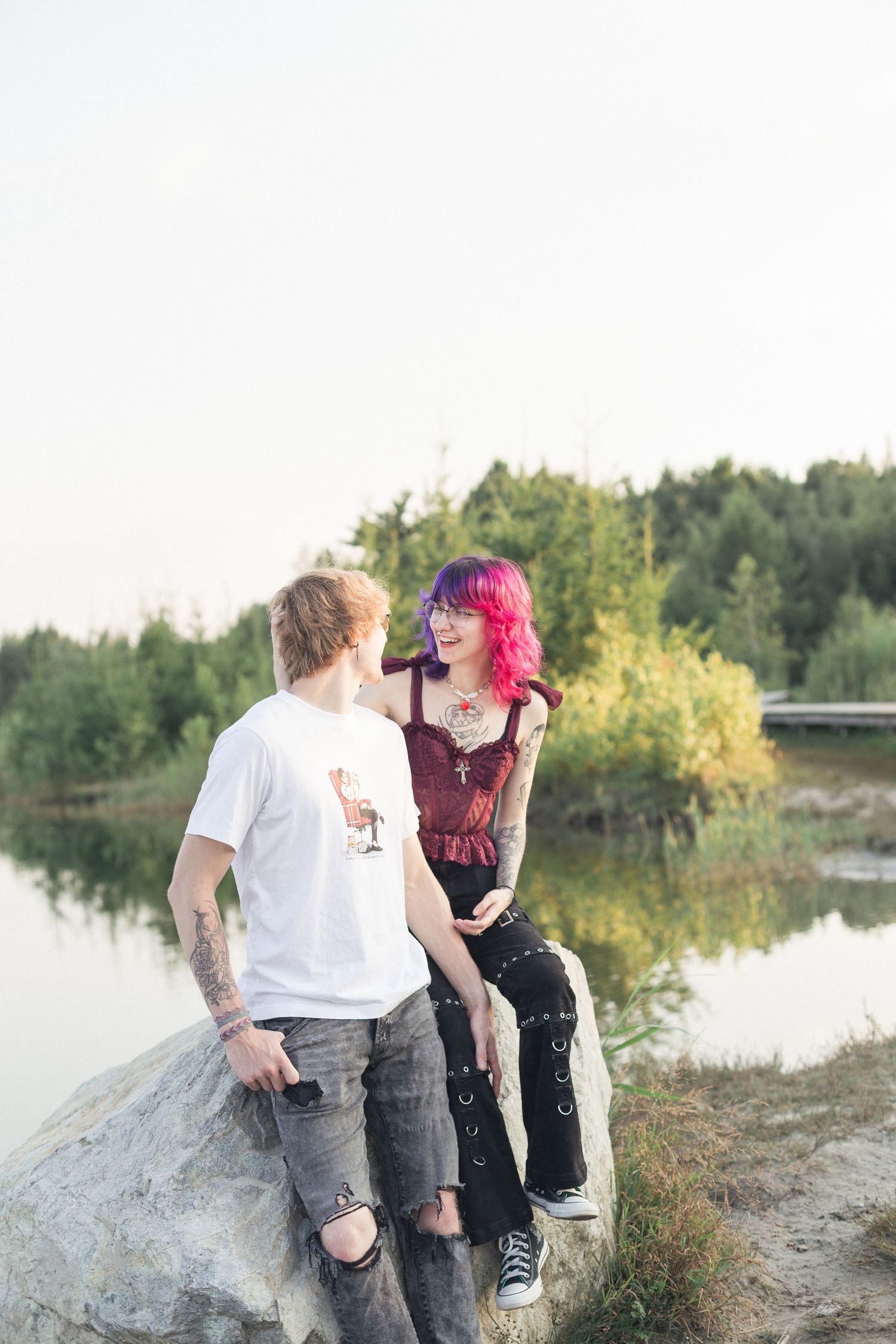 Un couple assis sur une roche près d'un lac, se regardant.
