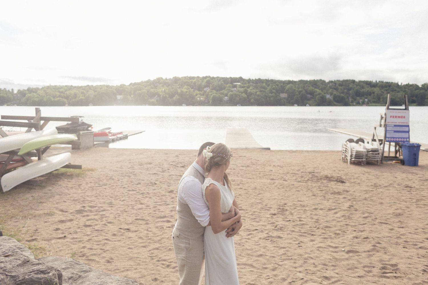 Un marié enlaçant sa femme dans sa robe de mariée, sur la plage.