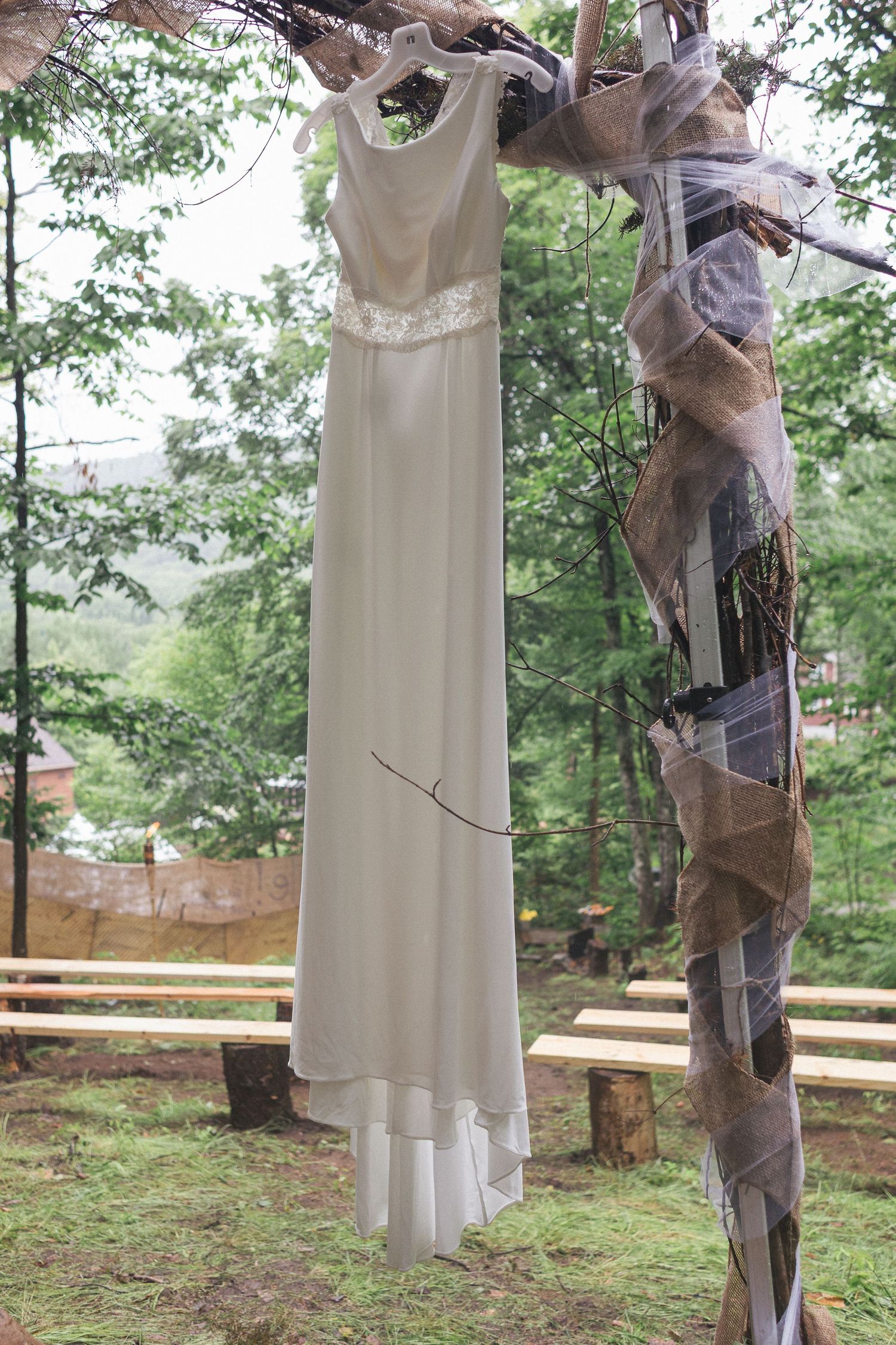 une robe de mariée blanche accrochée dans un décor de forêt et de nature.