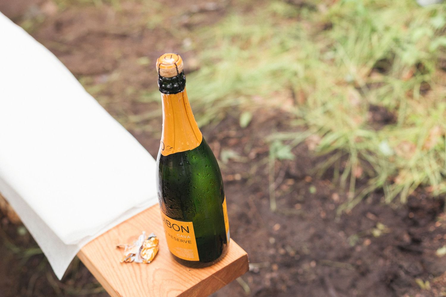 Une bouteille de champagne ouverte, sur un banc de bois.