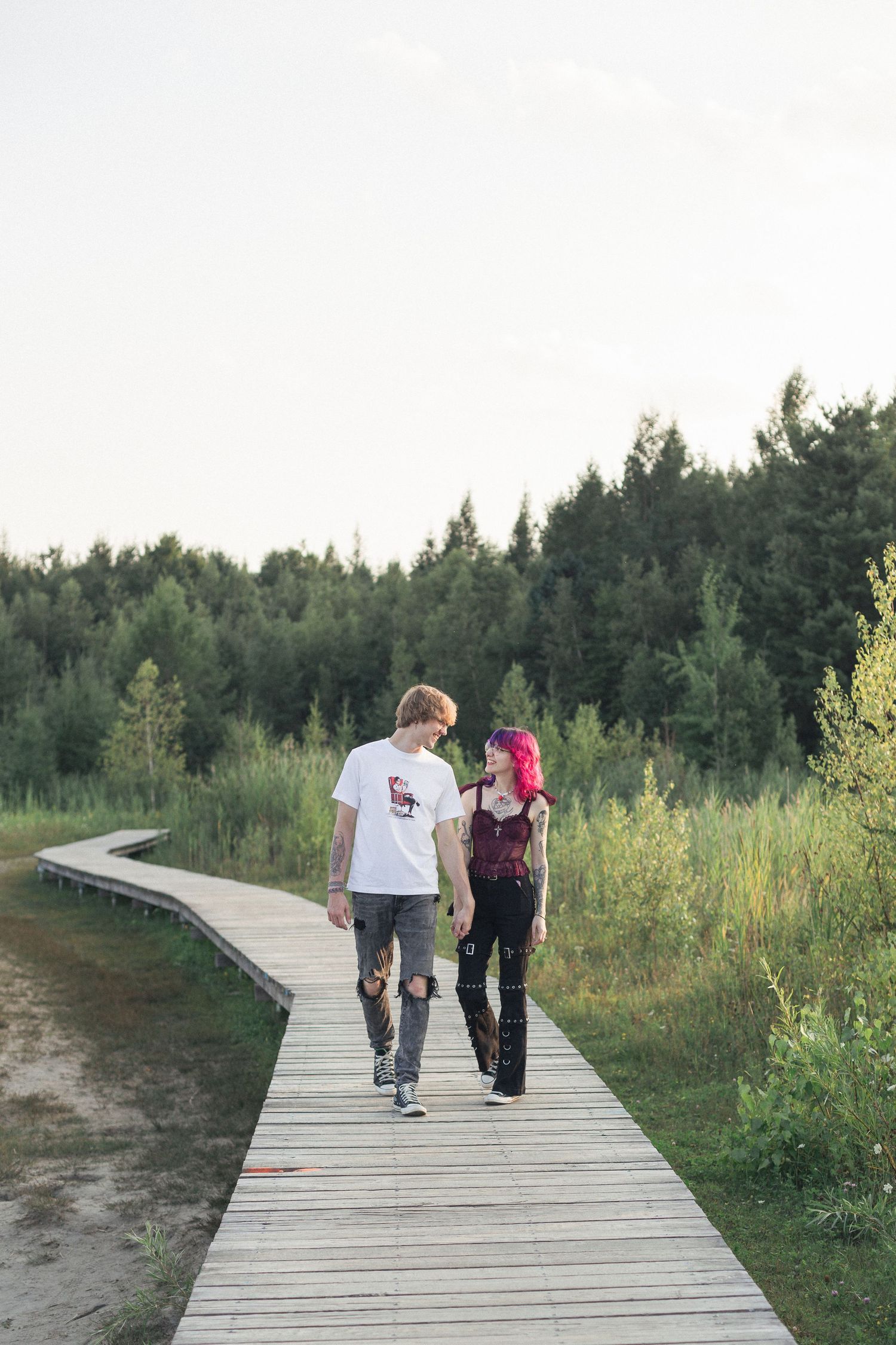 Un couple marchant ensemble sur un pont de bois dans la nature.