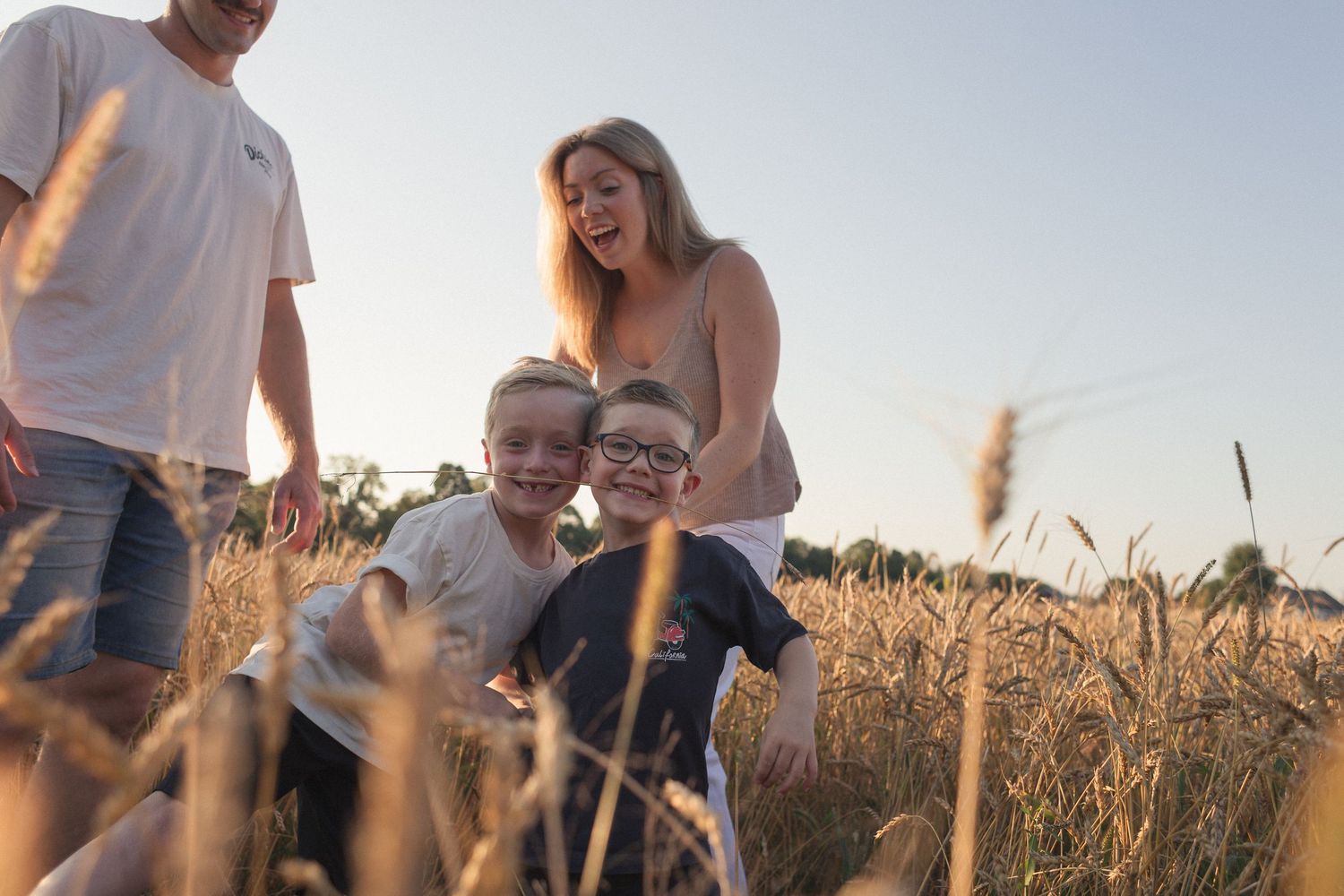 Une famille s'amusant avec le blé dans les champs lors d'une belle soirée d'été.