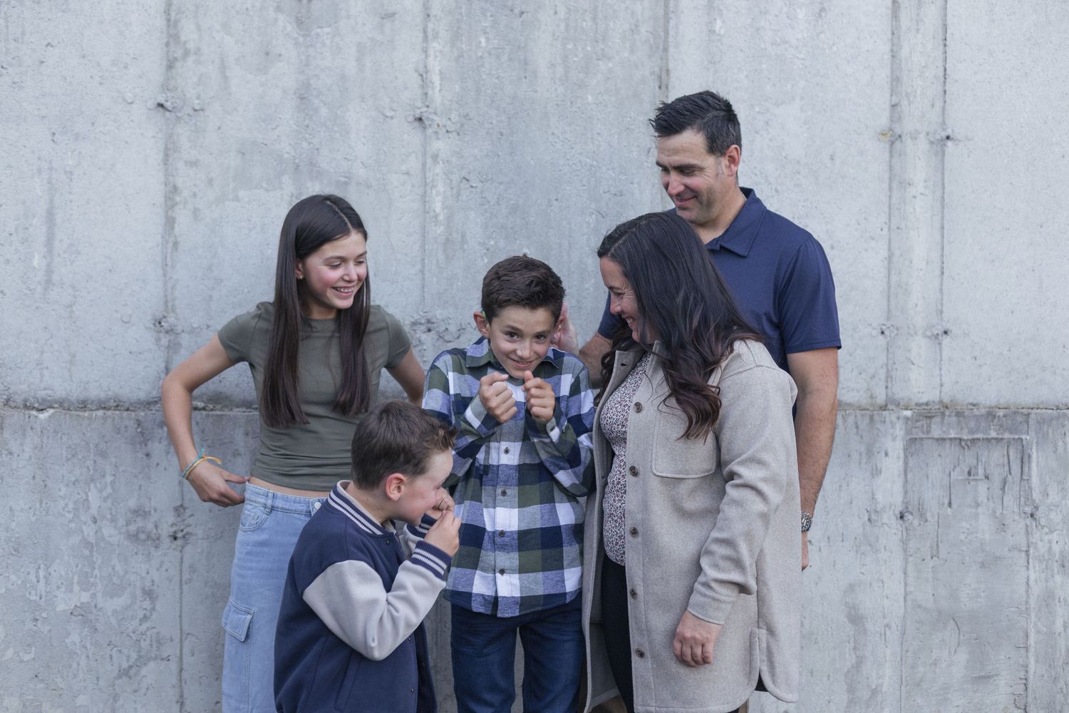 Une famille rigolant près d'un mur de béton.
