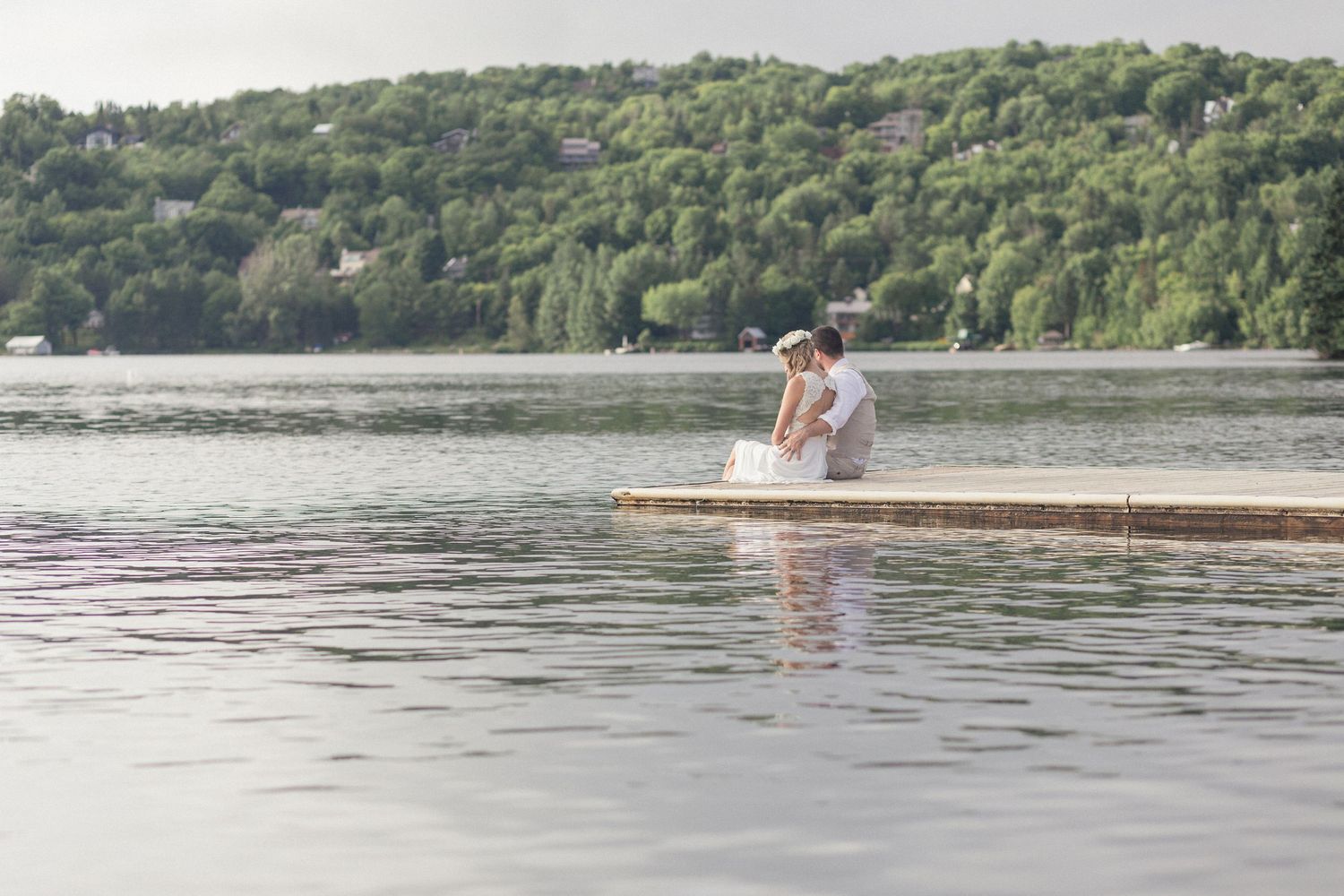Un couple assis au bord d'un quai, les pieds dans le lac.