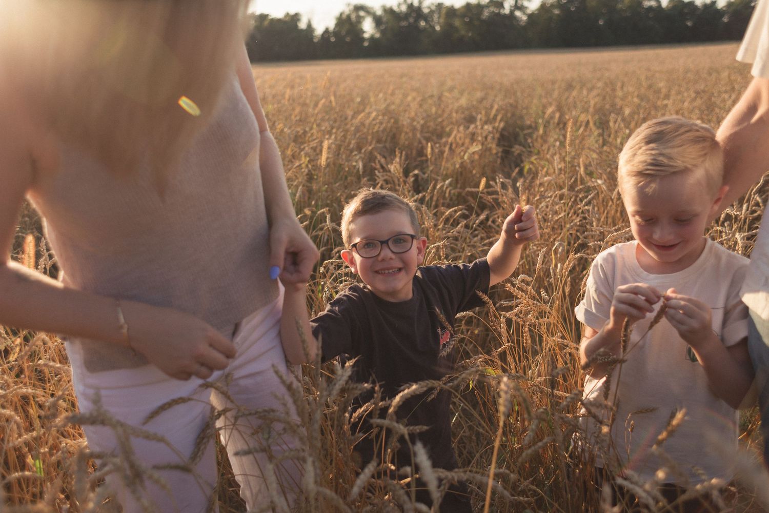 Une famille joyeuse qui joue dans le champ de blé au golden hour.