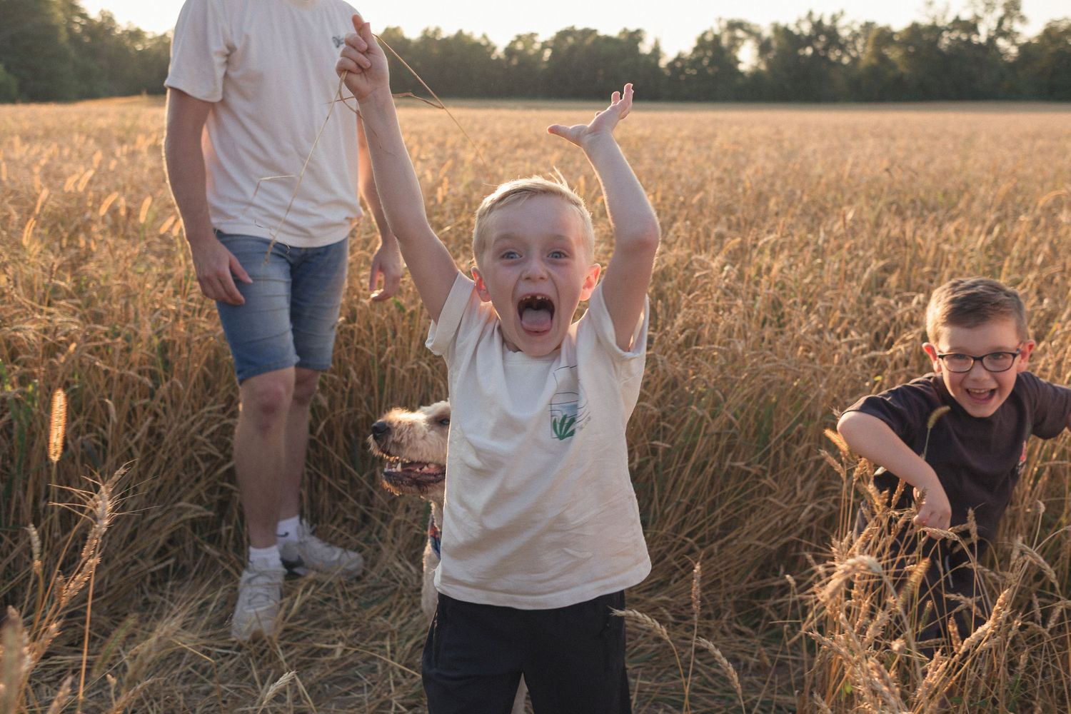 Des enfants qui s'amusent énergiquement dans un champ, enveloppés de lumière naturelle.