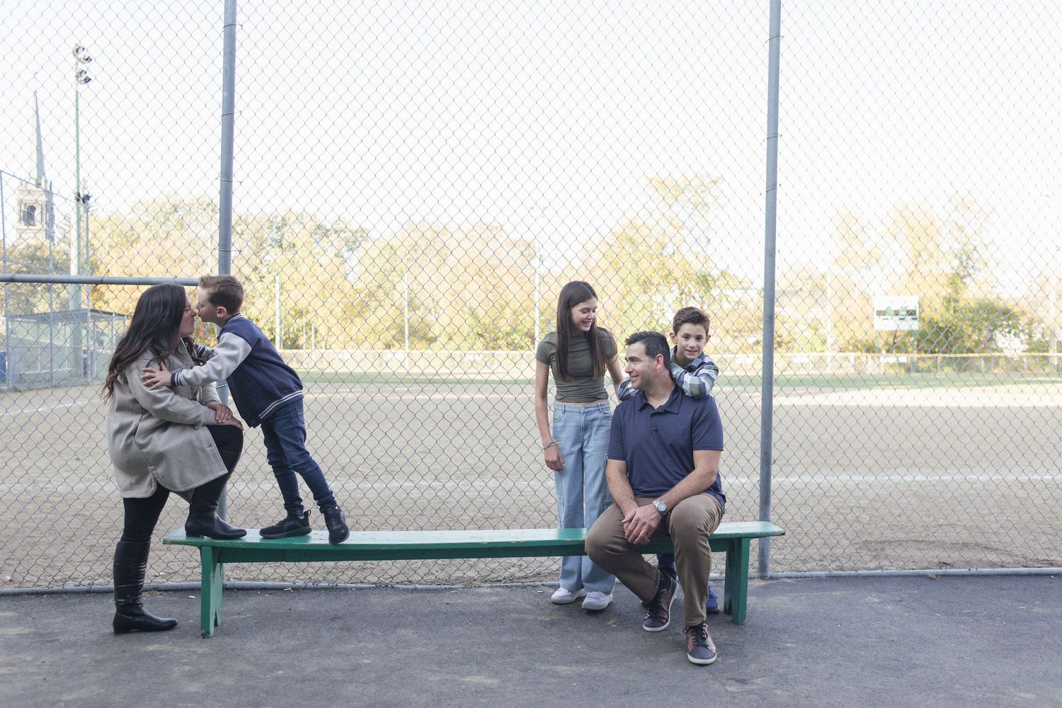 Une famille assise sur un banc, posant pour une séance photo au parc de baseball.