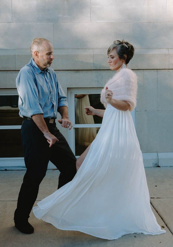 A couple dancing together in a romantic setting with the bride wearing a flowing white wedding dress.
