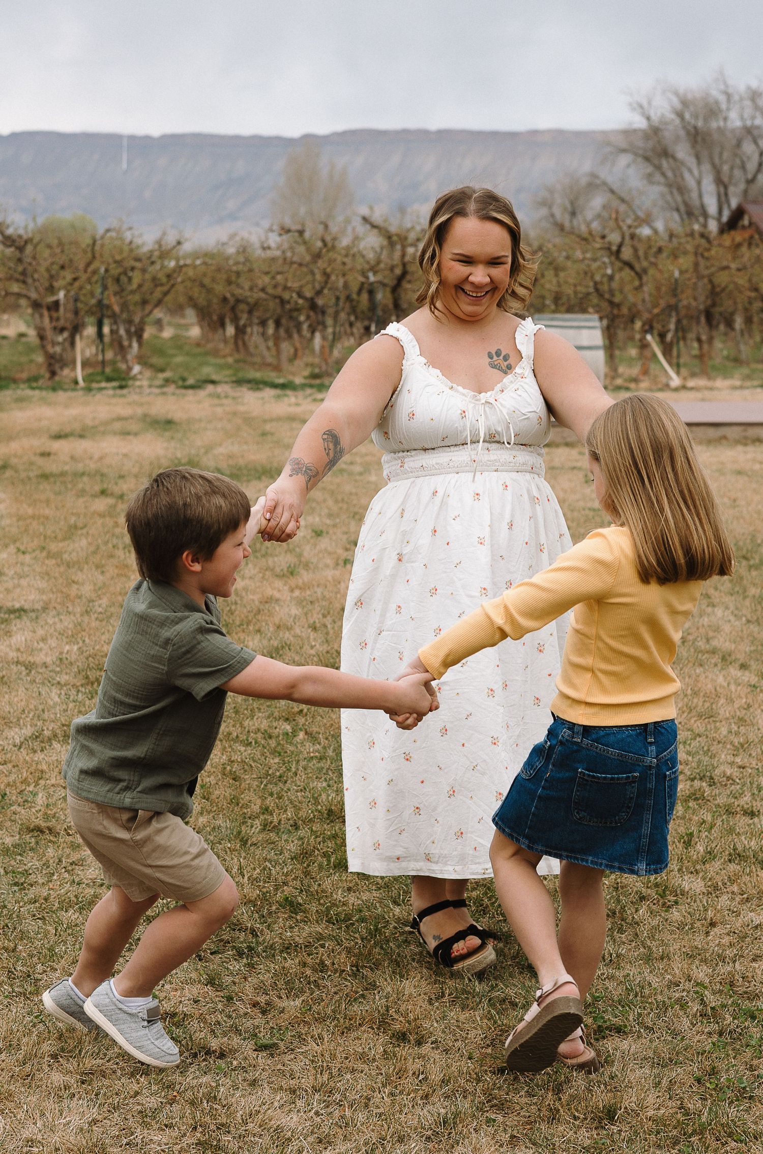 Series of playful shots of children chasing and running together in an open grassy field with trees in the background.