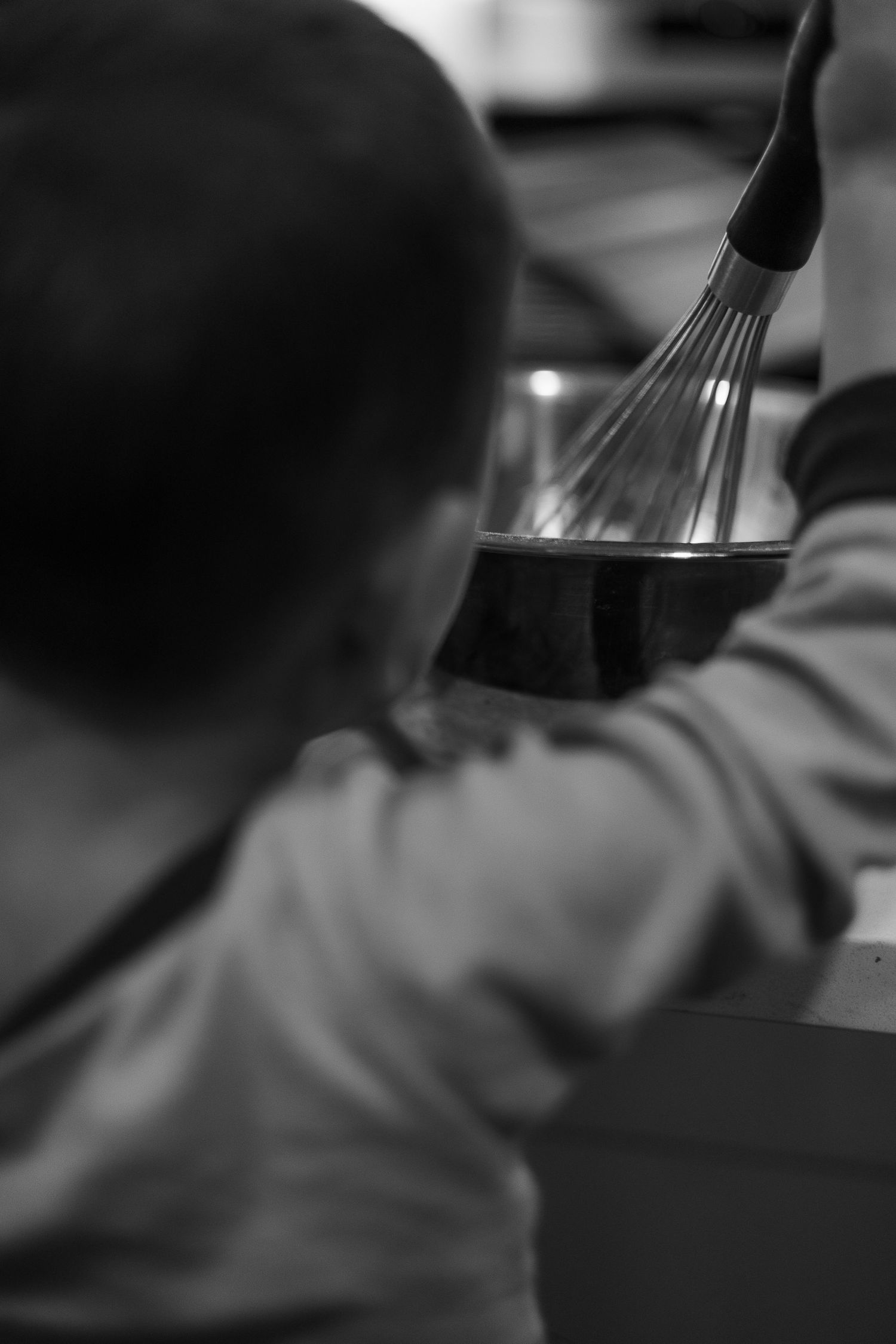 A black and white photograph shows someone playing piano keys in soft focus with dramatic lighting.