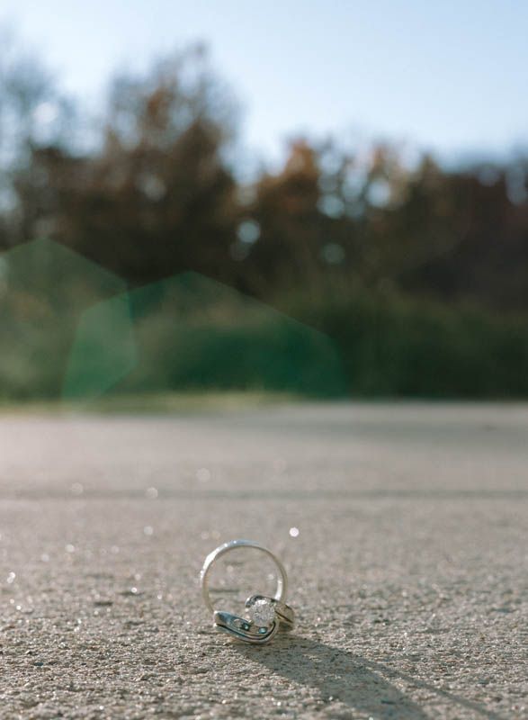 Wedding rings resting on a textured concrete surface in natural lighting.
