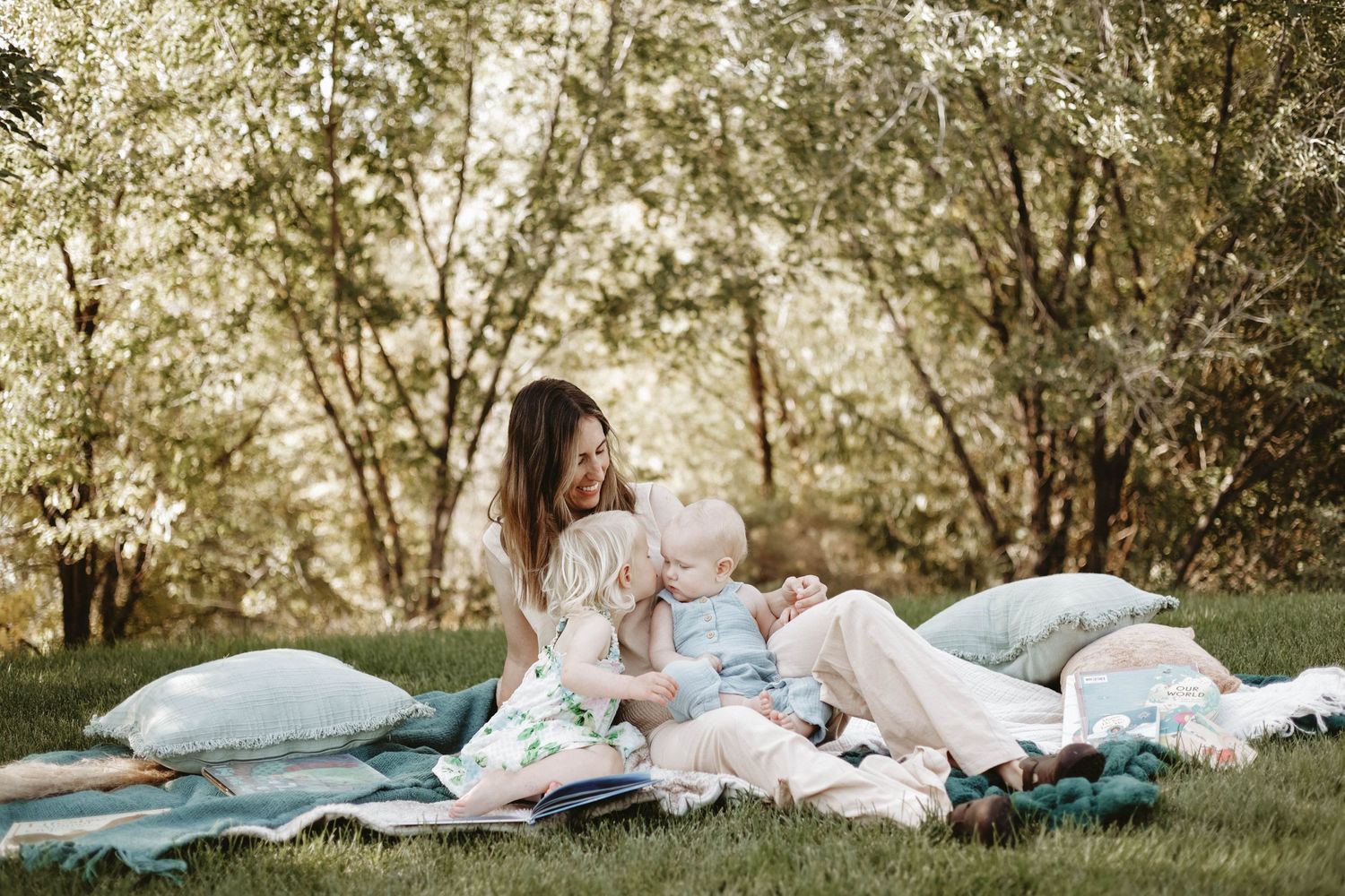 Family relaxing together on blankets under trees in a sunlit park.