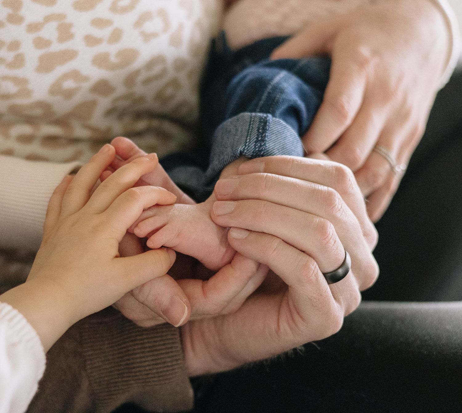 Close-up view of two hands clasped together in a tender moment showing a black wedding band.