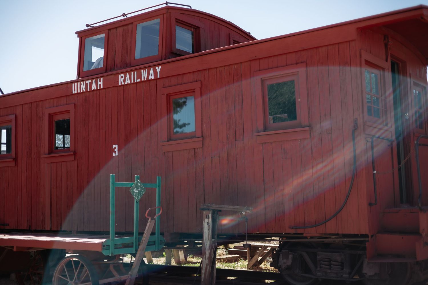 A series of vintage red train cars and cabooses parked at a railroad museum display.